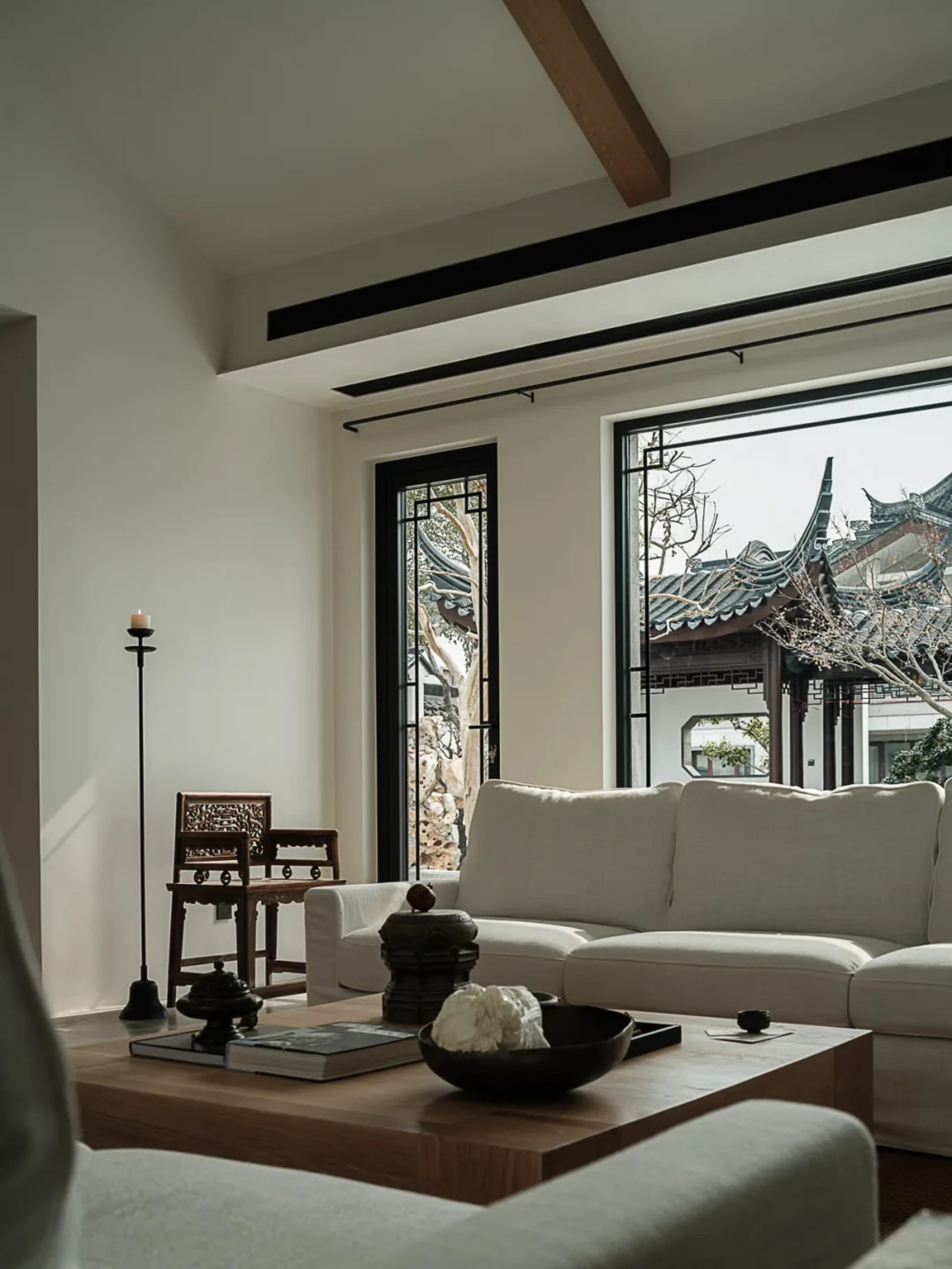 Modern living room featuring a white sofa, wooden coffee table, and large windows overlooking traditional Chinese architectur