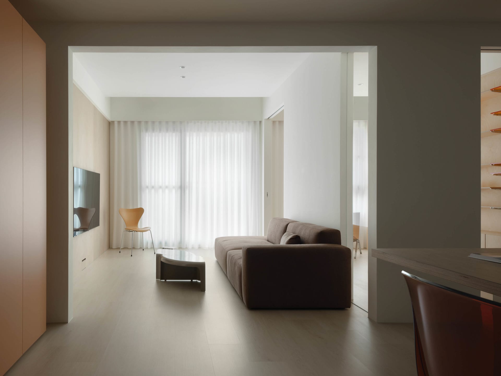 A modern living room featuring neutral-colored furnishings, minimalist design, and large windows allowing natural light to fl