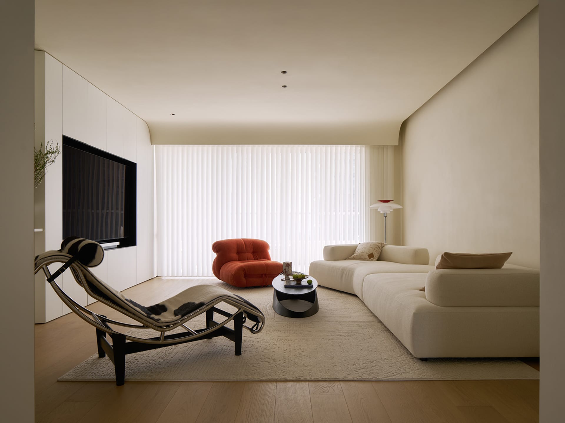 A modern minimalist living room with taupe-colored wooden flooring and a white sectional sofa with patterned pillows, accente