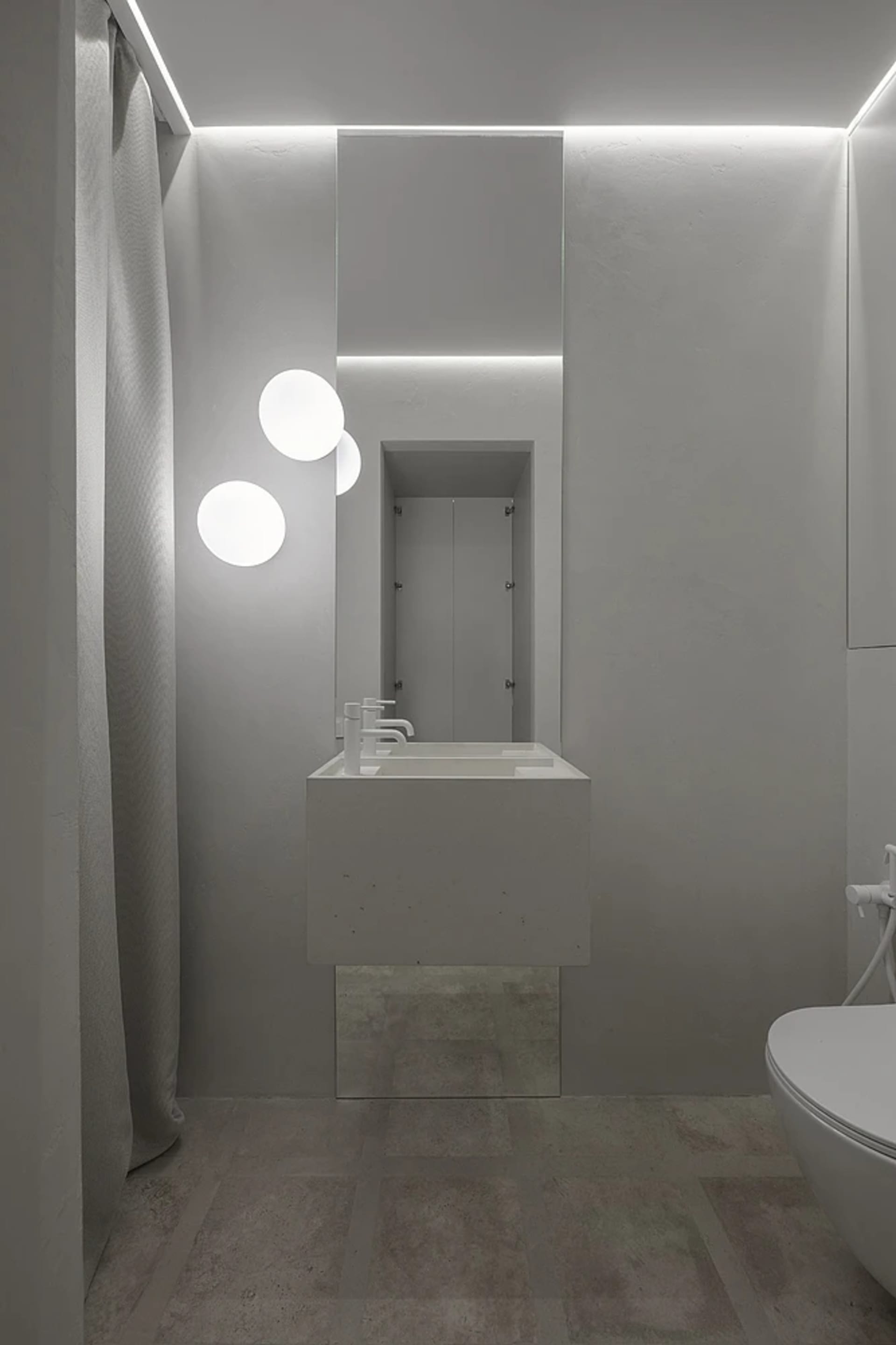 Modern minimalist bathroom with concrete surfaces, glass shower enclosure, and metal fixtures.