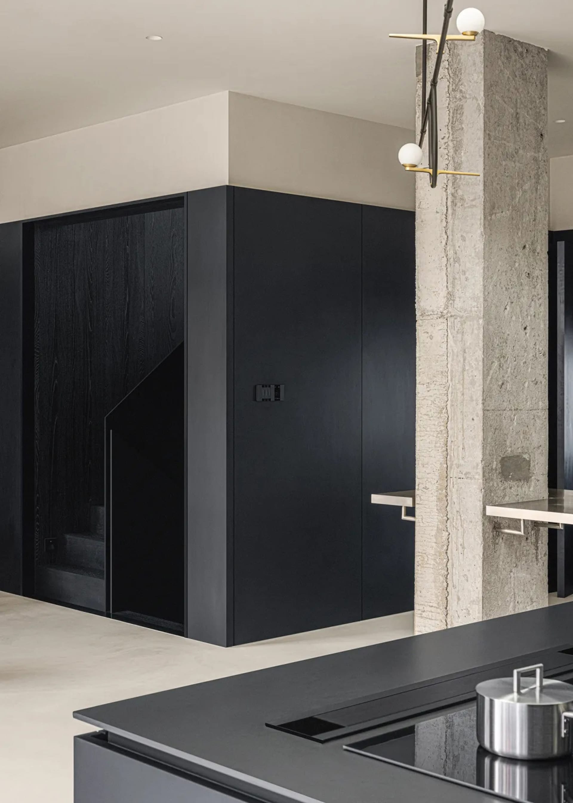 A modern kitchen with black wooden cabinetry and a concrete wall.