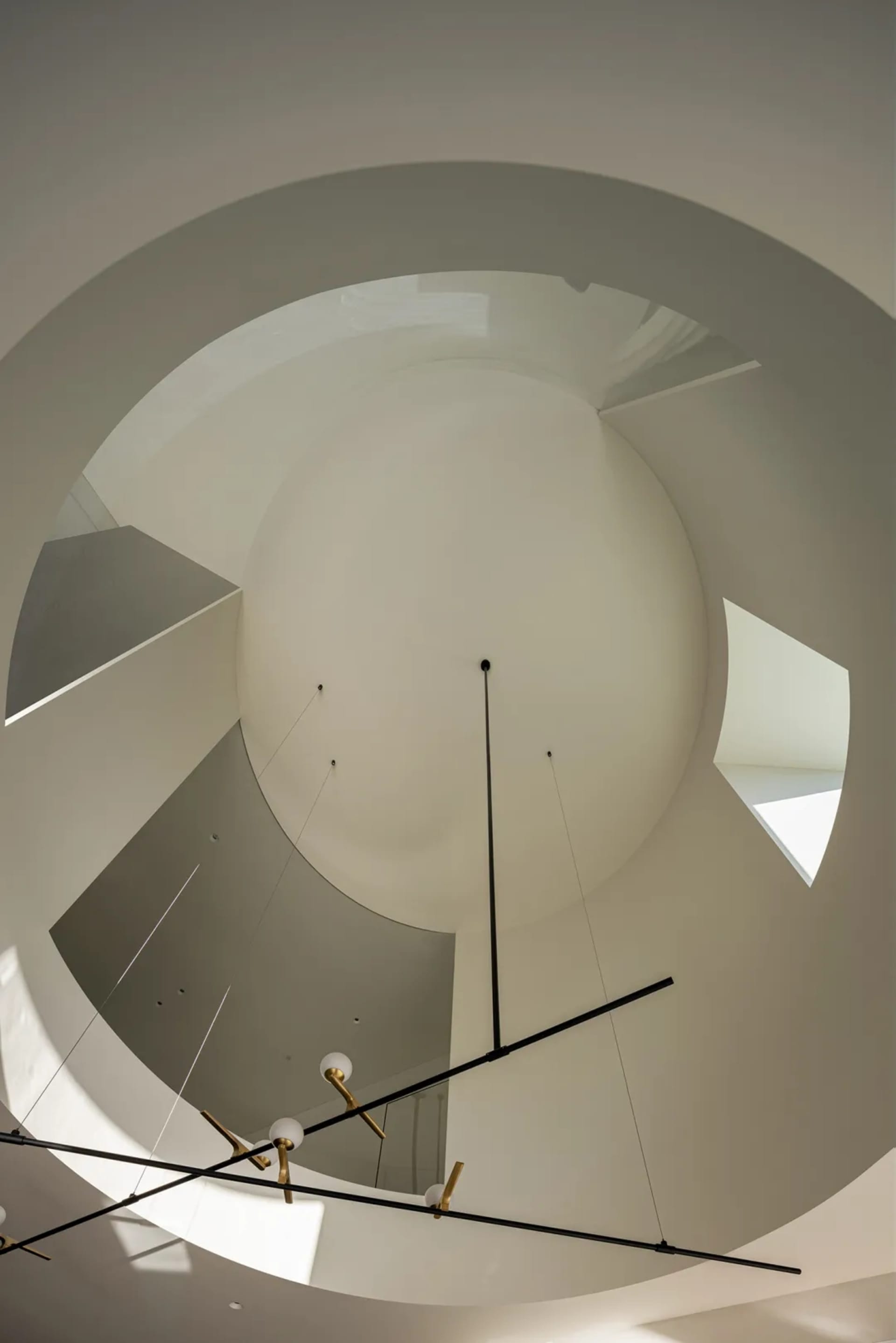 A modern circular ceiling light fixture hanging from a high ceiling.