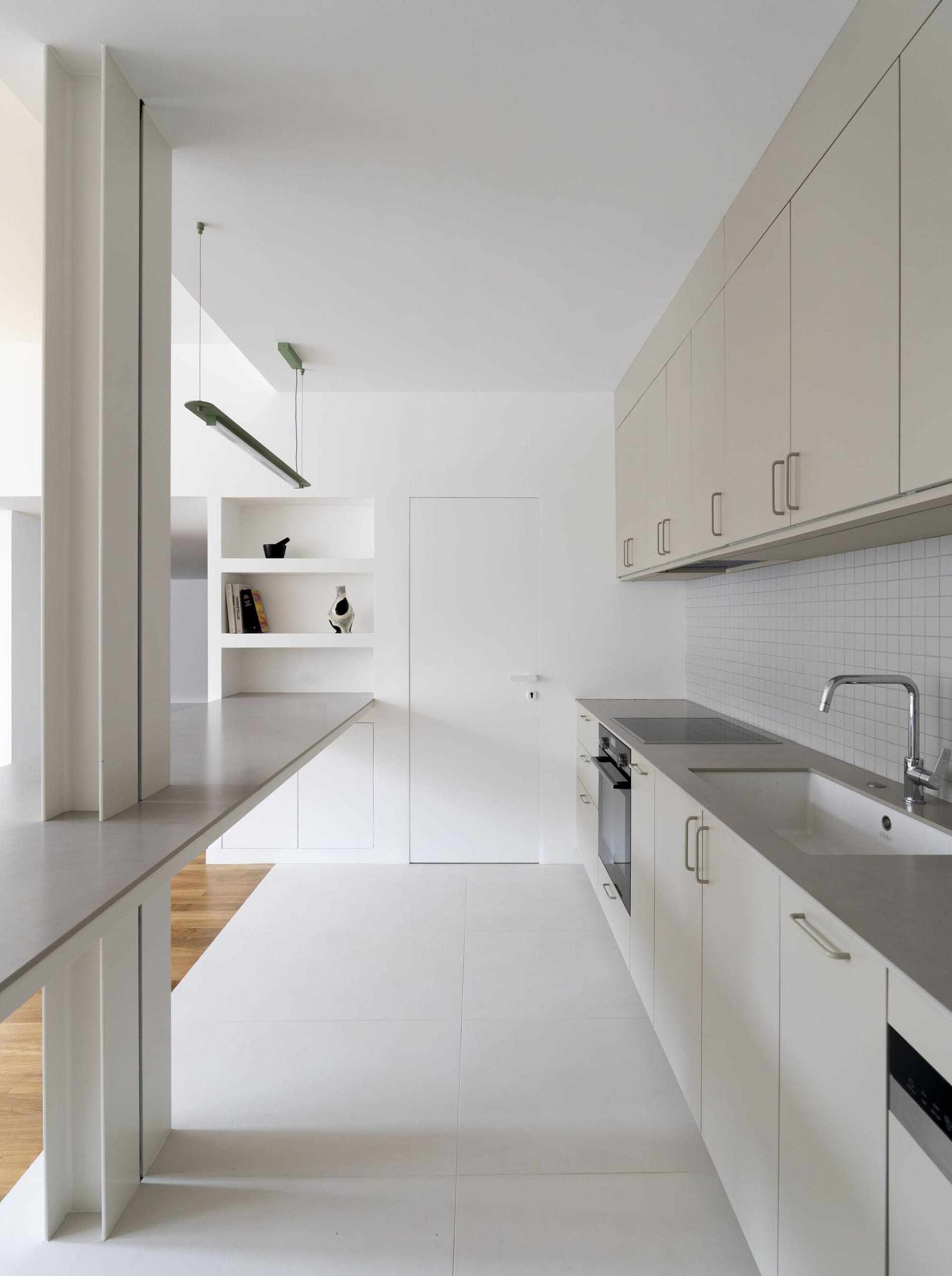 Modern minimalist kitchen with white walls and concrete countertops.