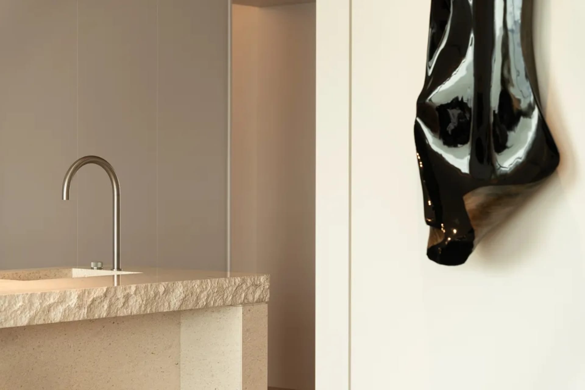 A minimalist bathroom with a sink made of natural stone and a metallic faucet.