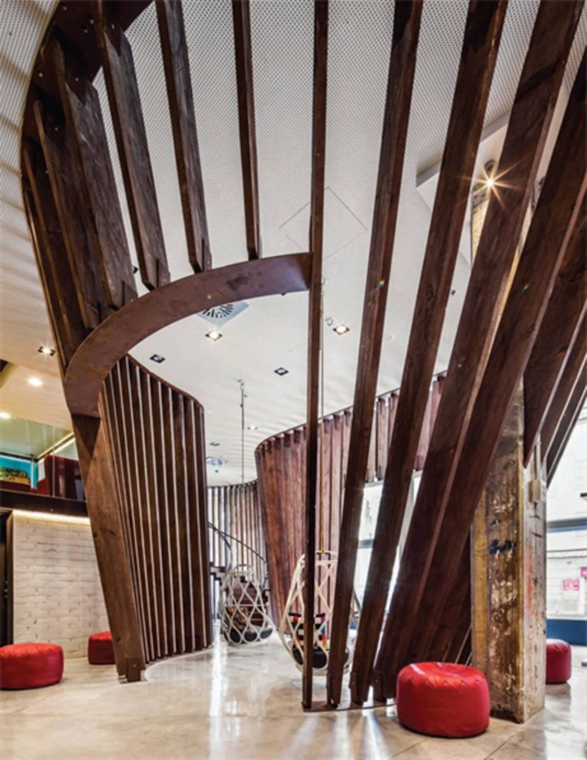 A modern office space with exposed wooden beams and a geometric staircase.