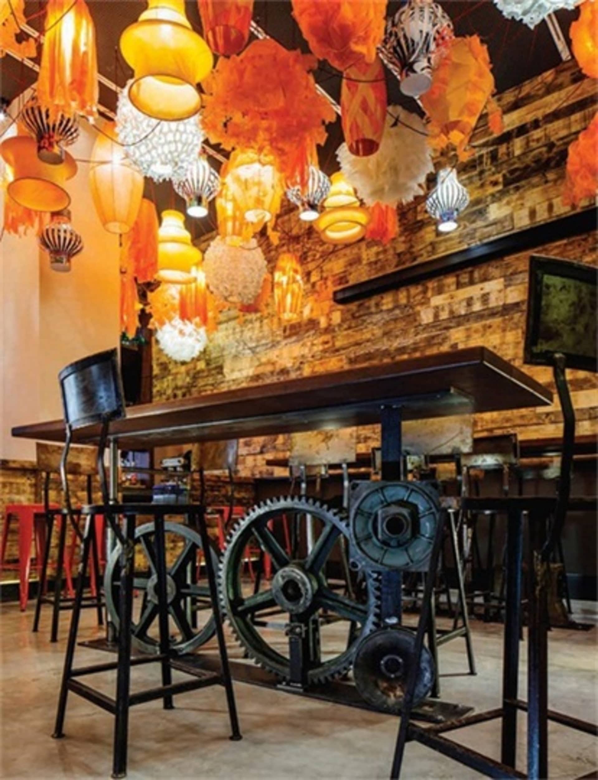 An industrial-themed restaurant interior with metal, wood, concrete, and fabric elements.