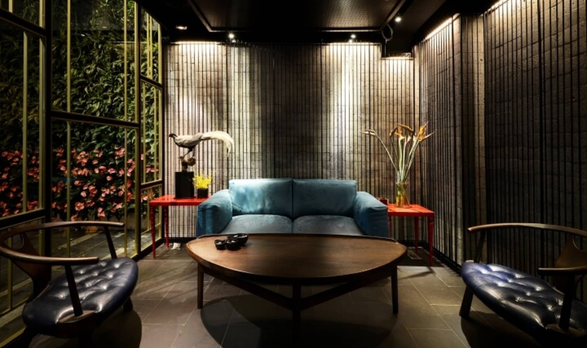 A modern living room with a metallic accent wall, blue sofa, and round wooden coffee table.