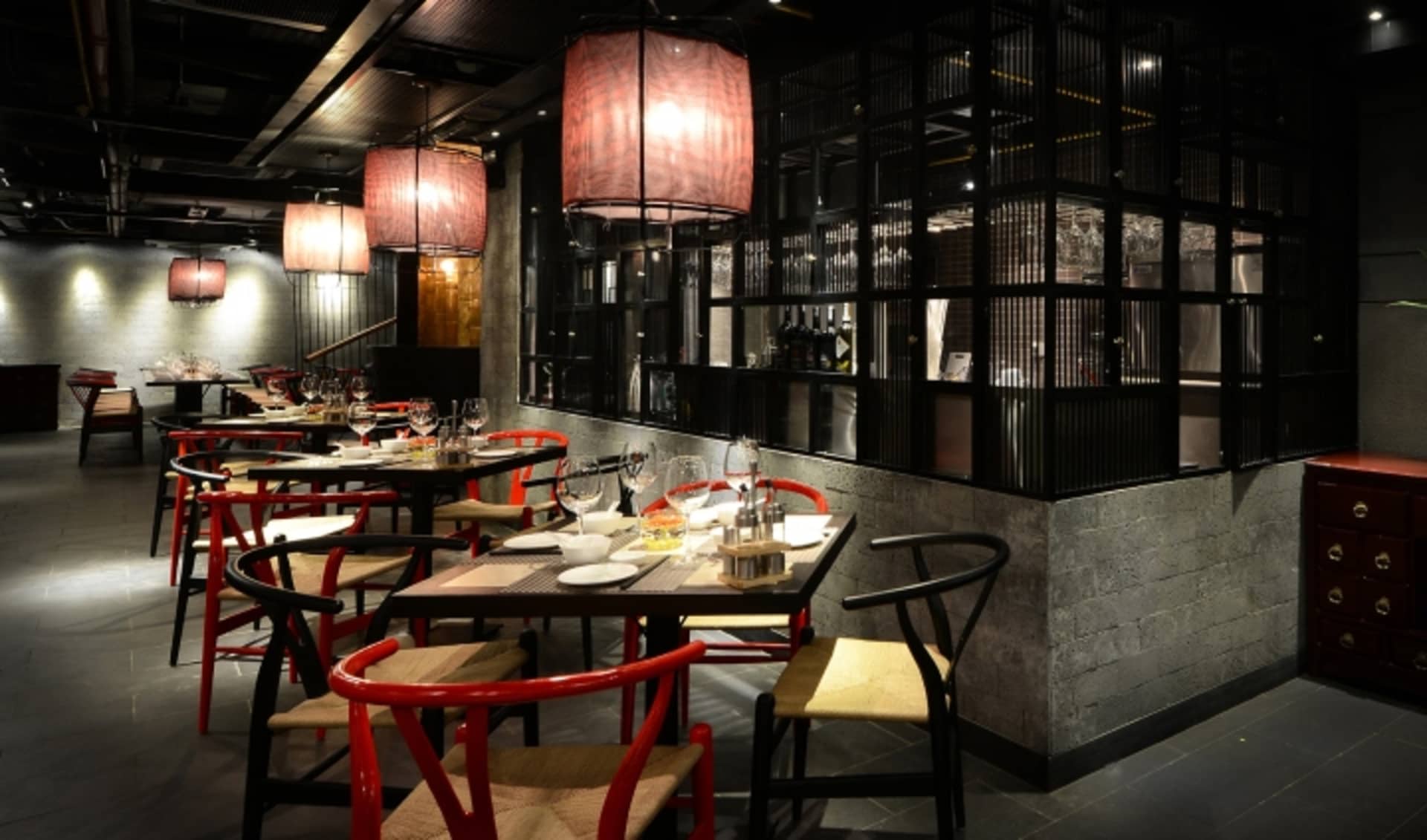 一間當代餐廳，配有紅黑家具、木製餐椅與混凝土牆面。