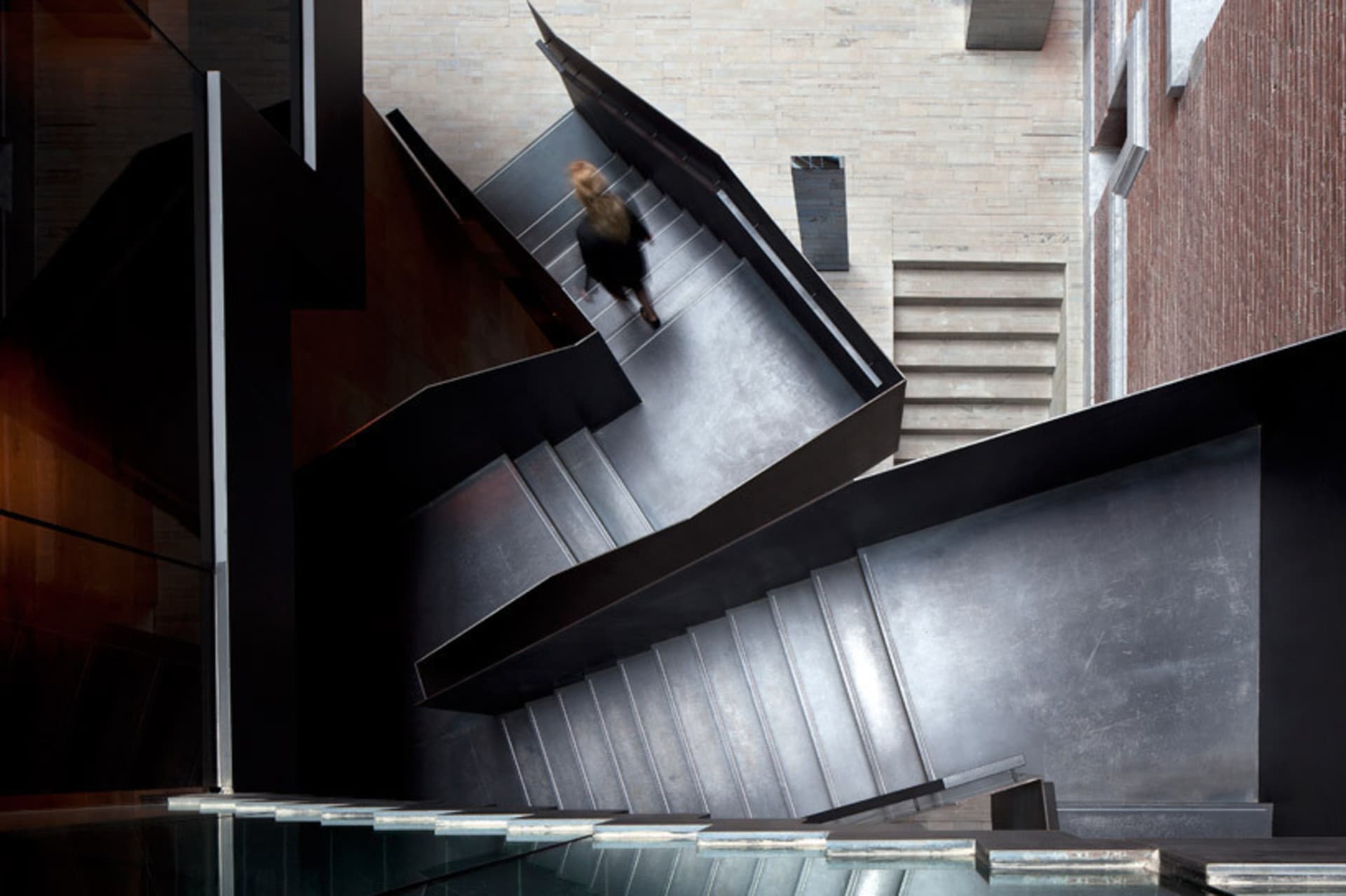 A modern, metal interior with a spiral staircase and a woman walking down the stairs.
