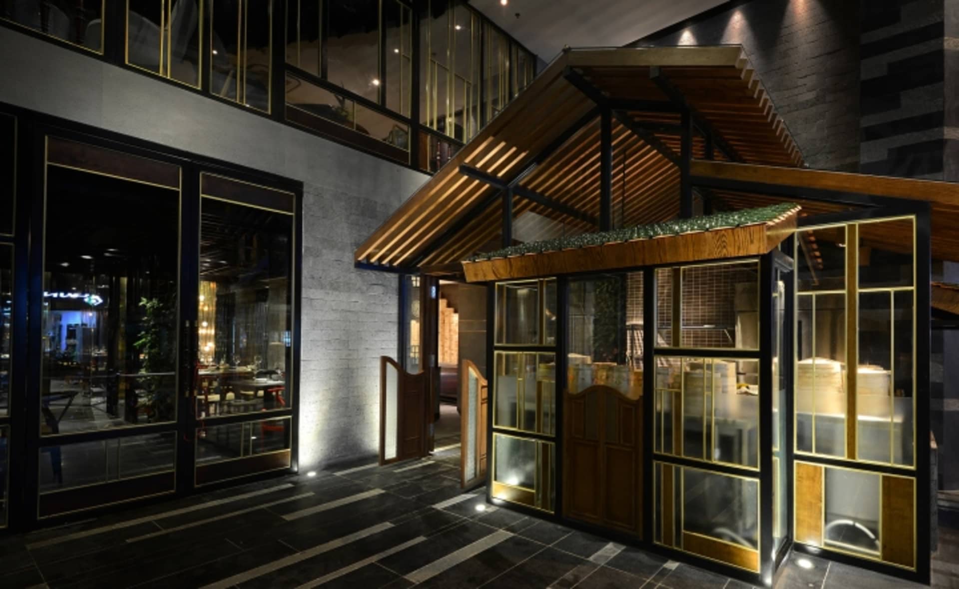 A modern restaurant exterior with wooden accents, glass panes, and concrete walls.