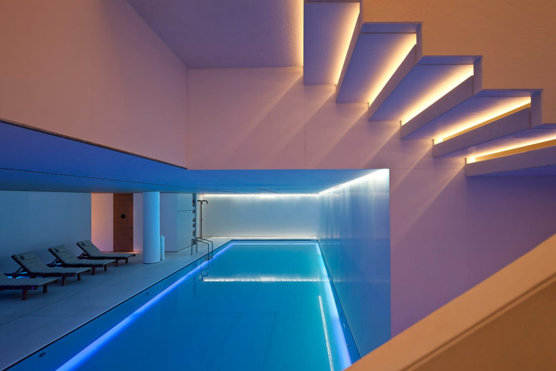 Swimming pool with minimalist, illuminated stairs made of glass