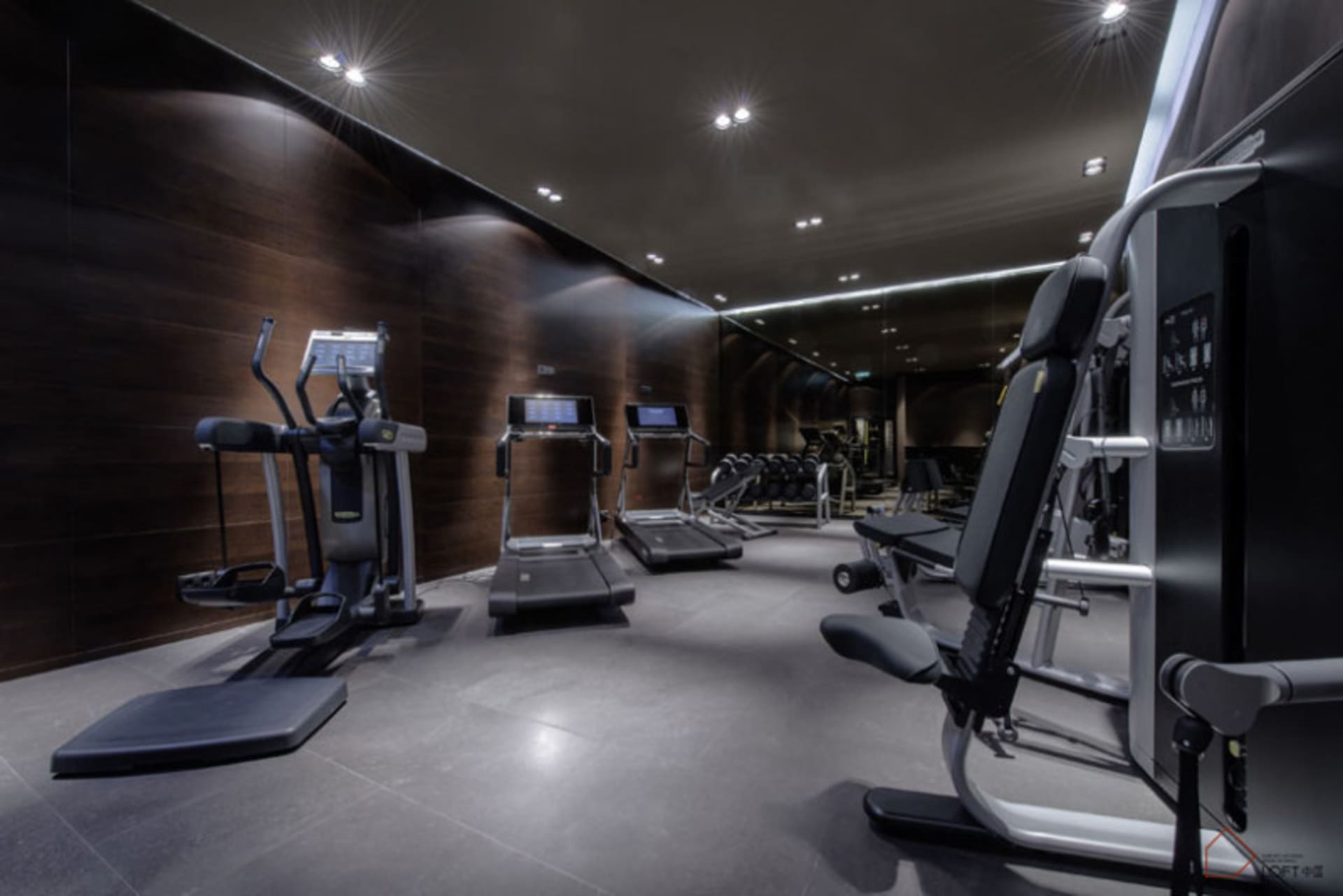 A modern gym with dark interior features steel and glass materials.