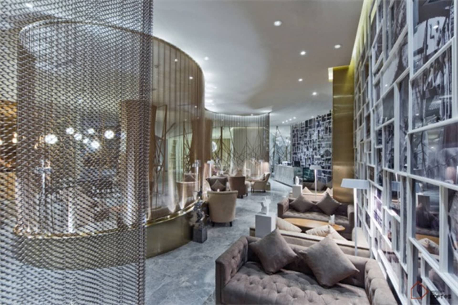 Modern hotel lounge with metal chain curtains, glass tables, and plush seating.