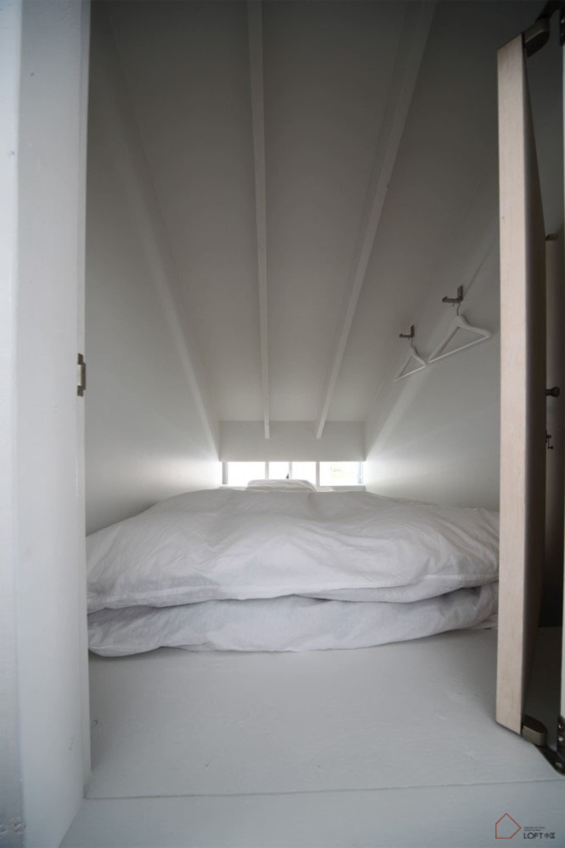 White bedding on a bed in a minimalist modern loft bedroom