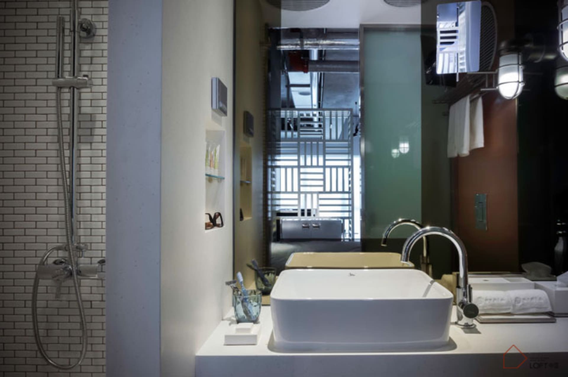 Modern bathroom with a concrete sink, white counter, tiled shower, and industrial lighting.