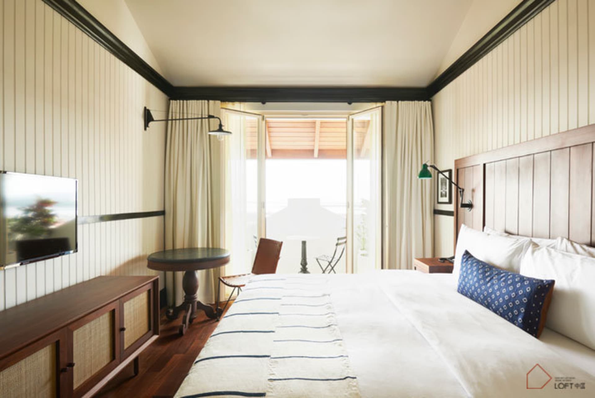 Modern bedroom featuring a white bed with wood details and a striped blanket.