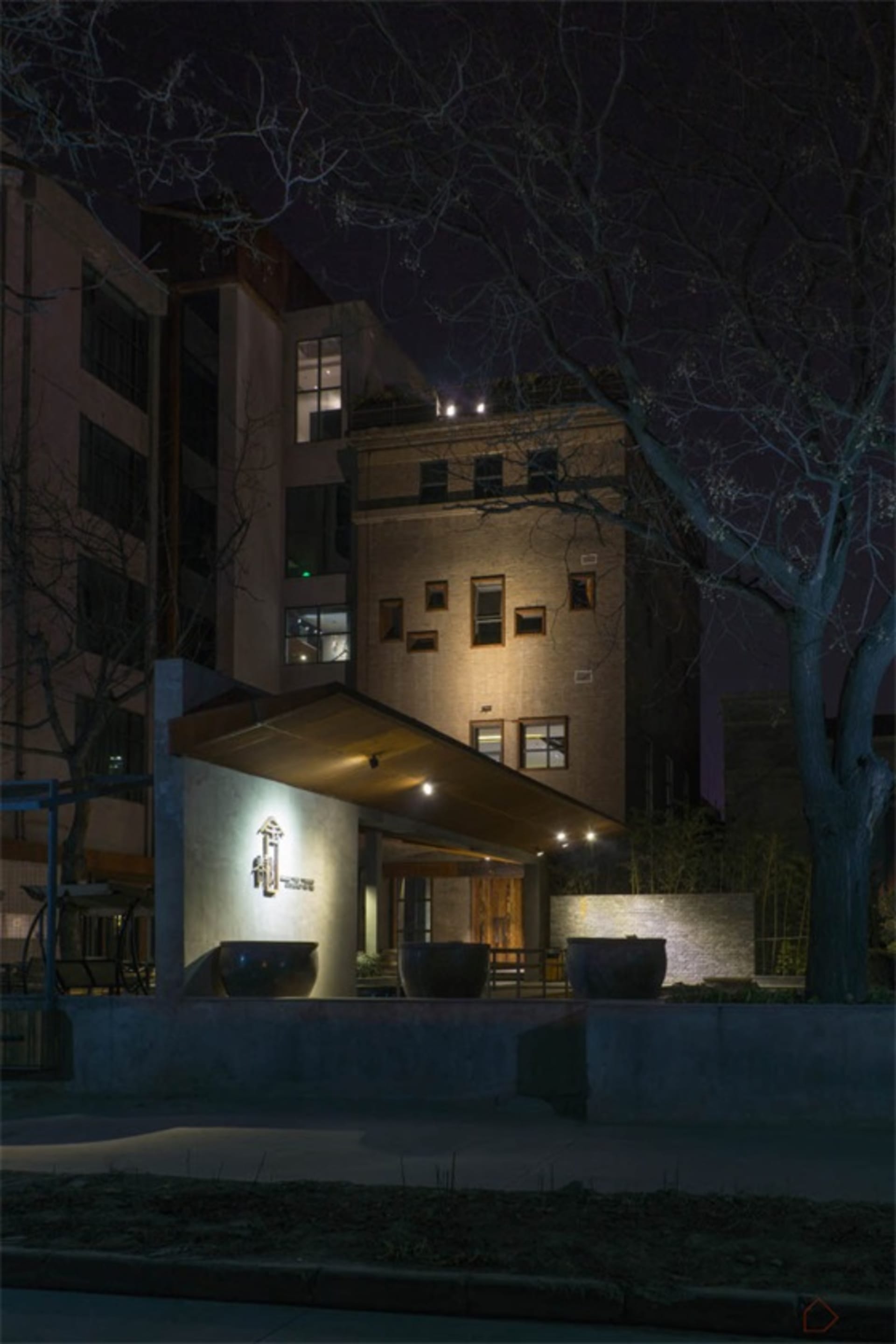 Modern building with brick exterior at night, illuminated by warm lights.