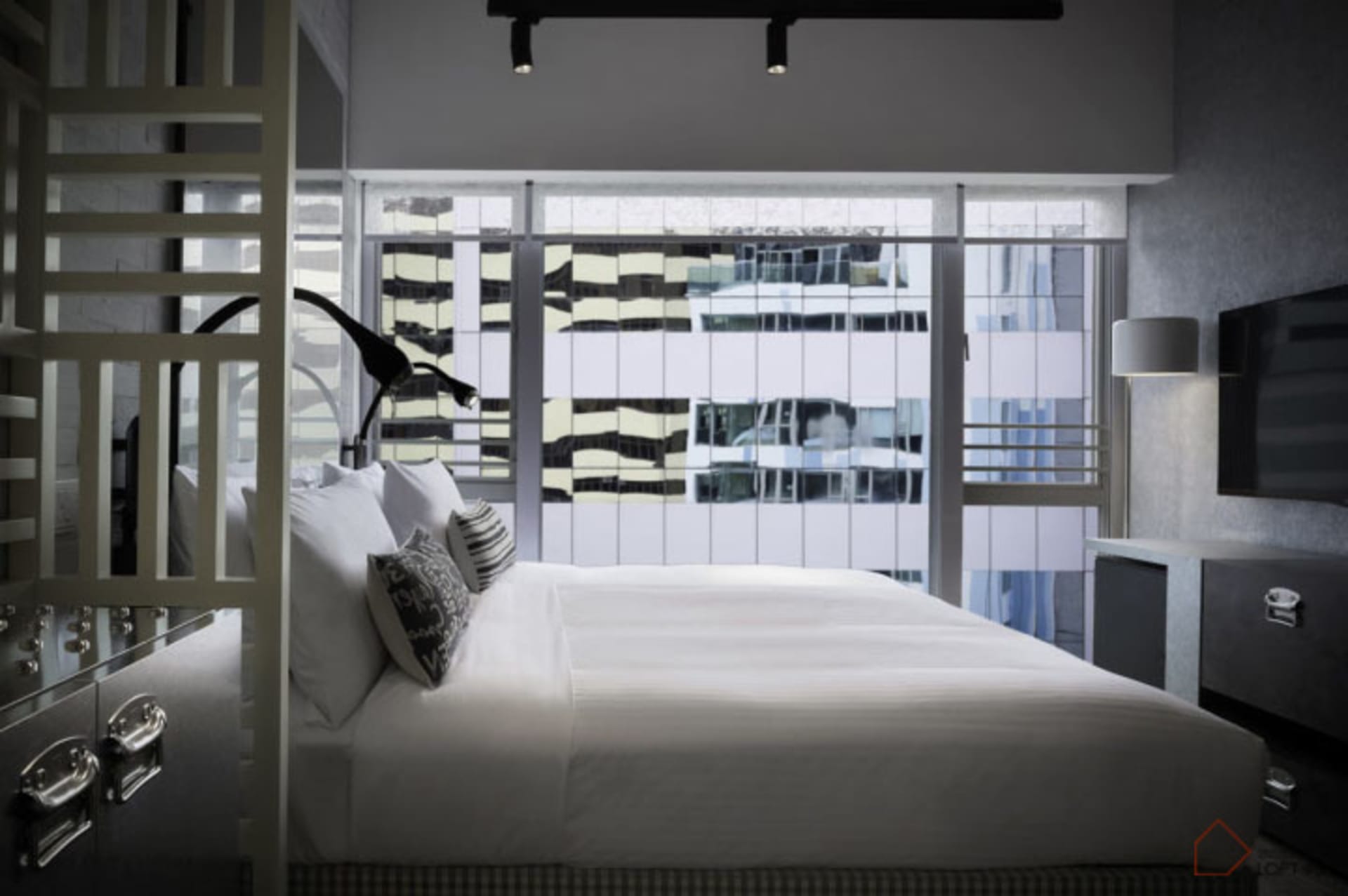 Clean, modern bedroom with a minimalist aesthetic, featuring a sleek bed with white bedding, and a large window offering city