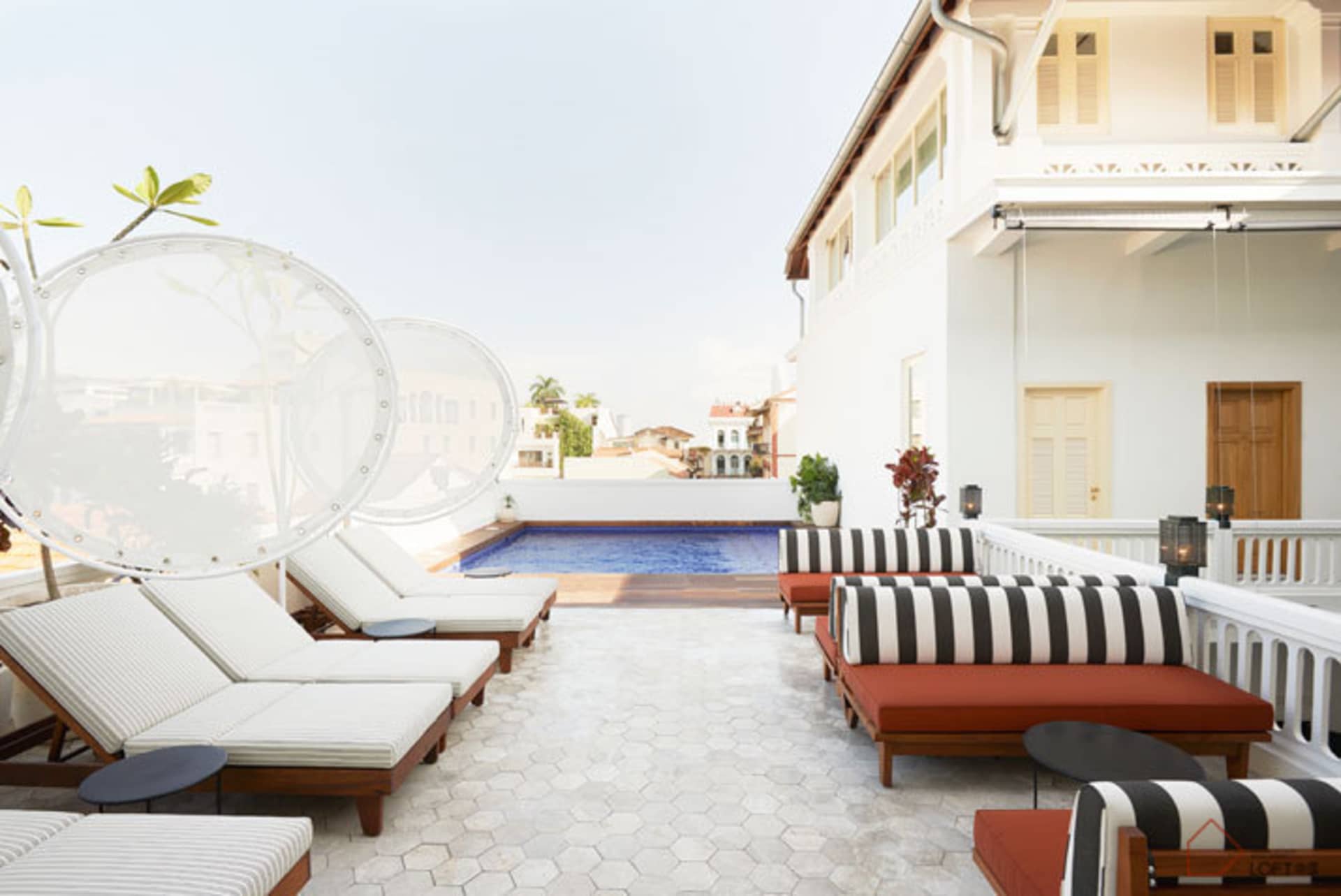 Modern hotel terrace with wooden lounge chairs, glass walls, and a cement patio