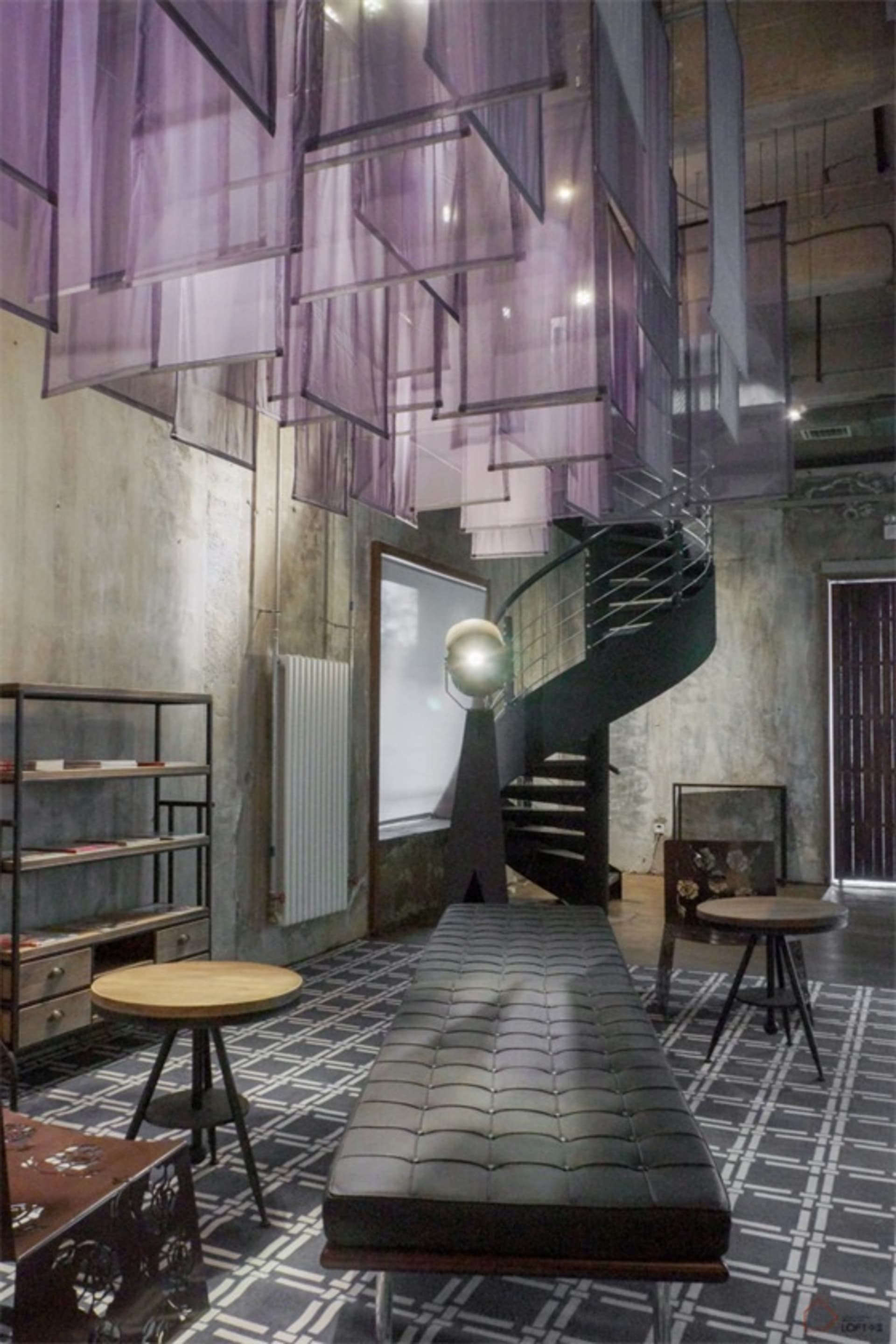 Indoor space featuring modern industrial design elements including metal, fabric, concrete, and glass.