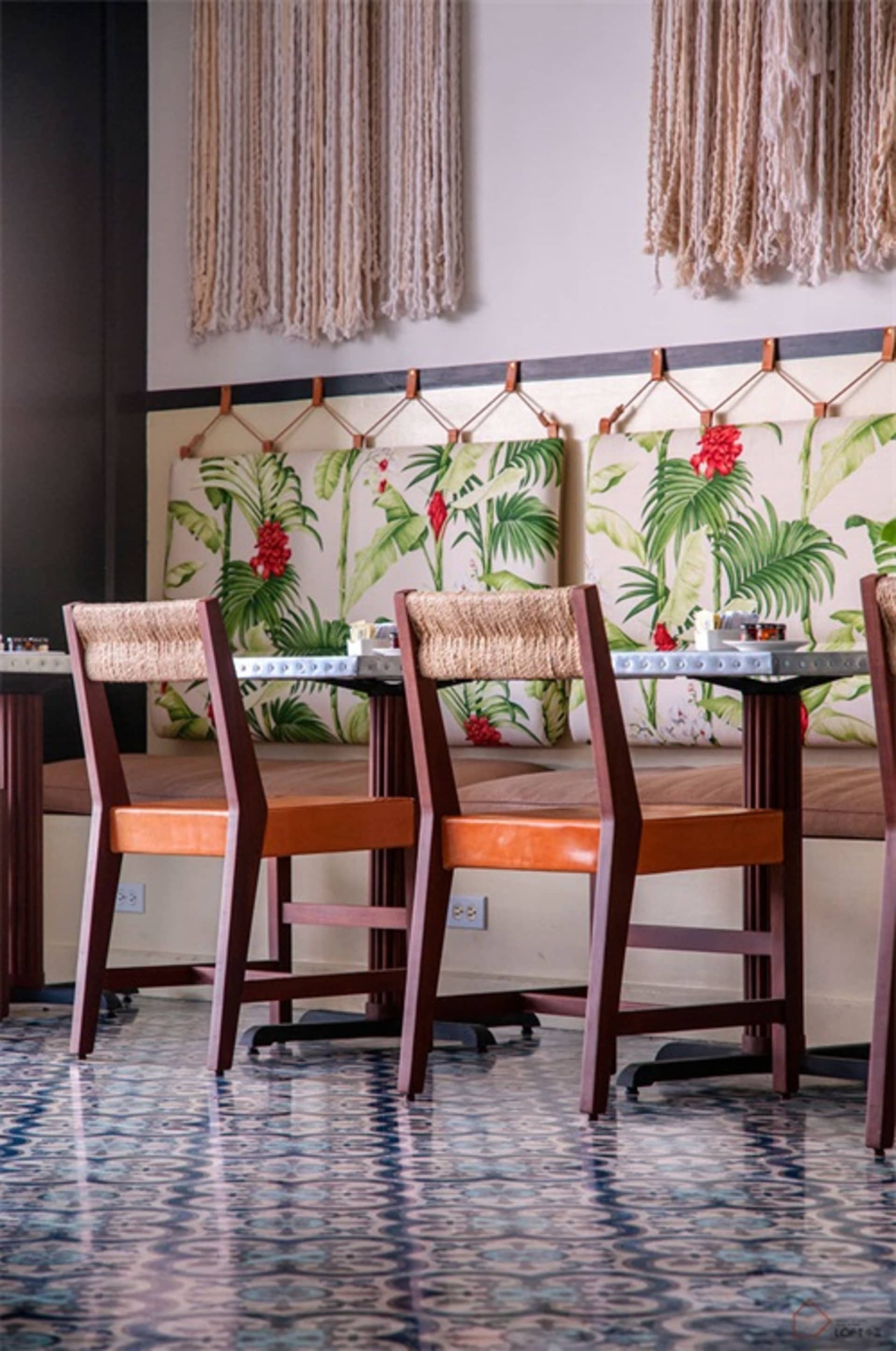 A photograph of a restaurant interior featuring textured striped polyester canvas walls, wooden chairs with orange cushions, 