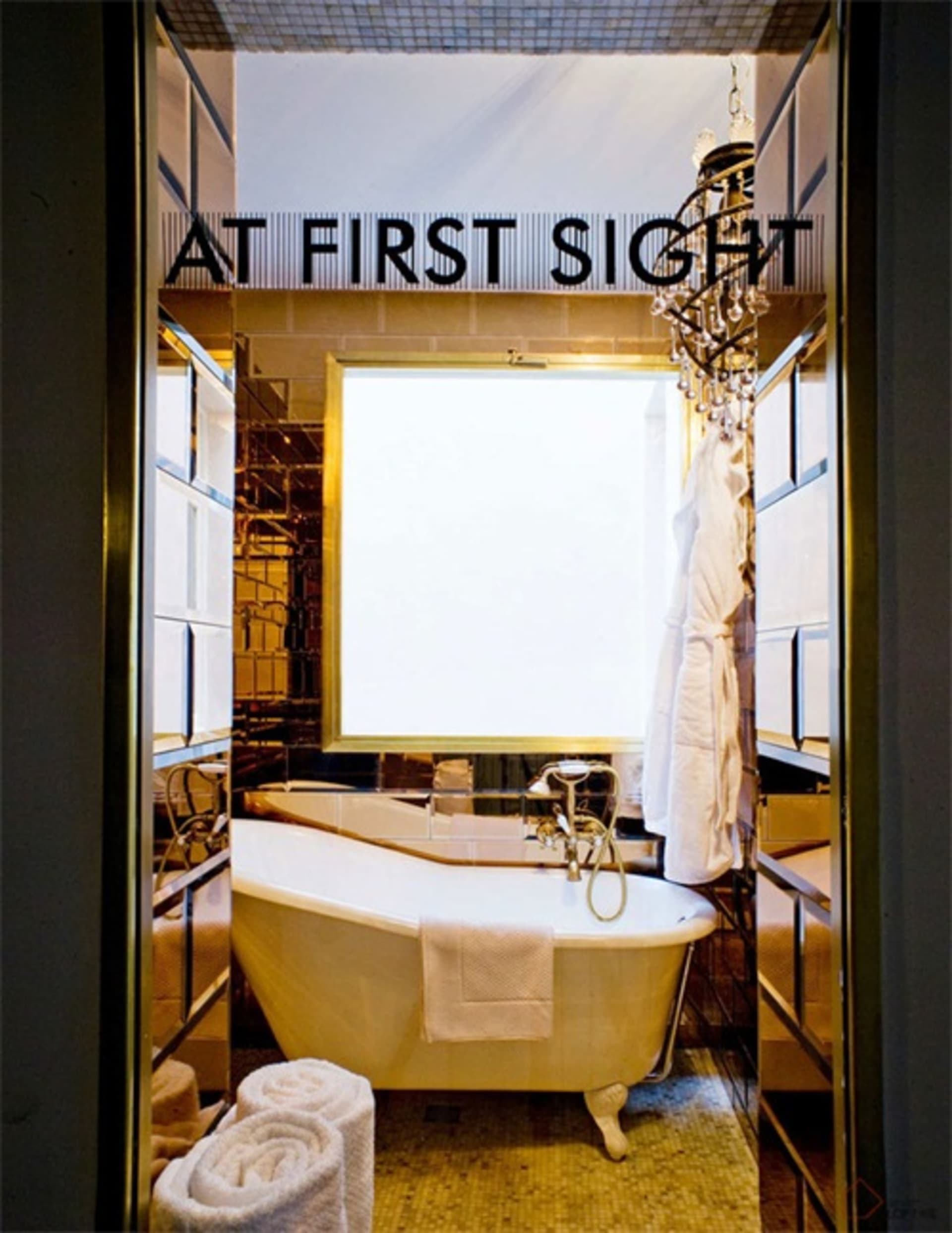 Modern bathroom with white bathtub, crystal chandelier, and golden mosaic floor tiles.