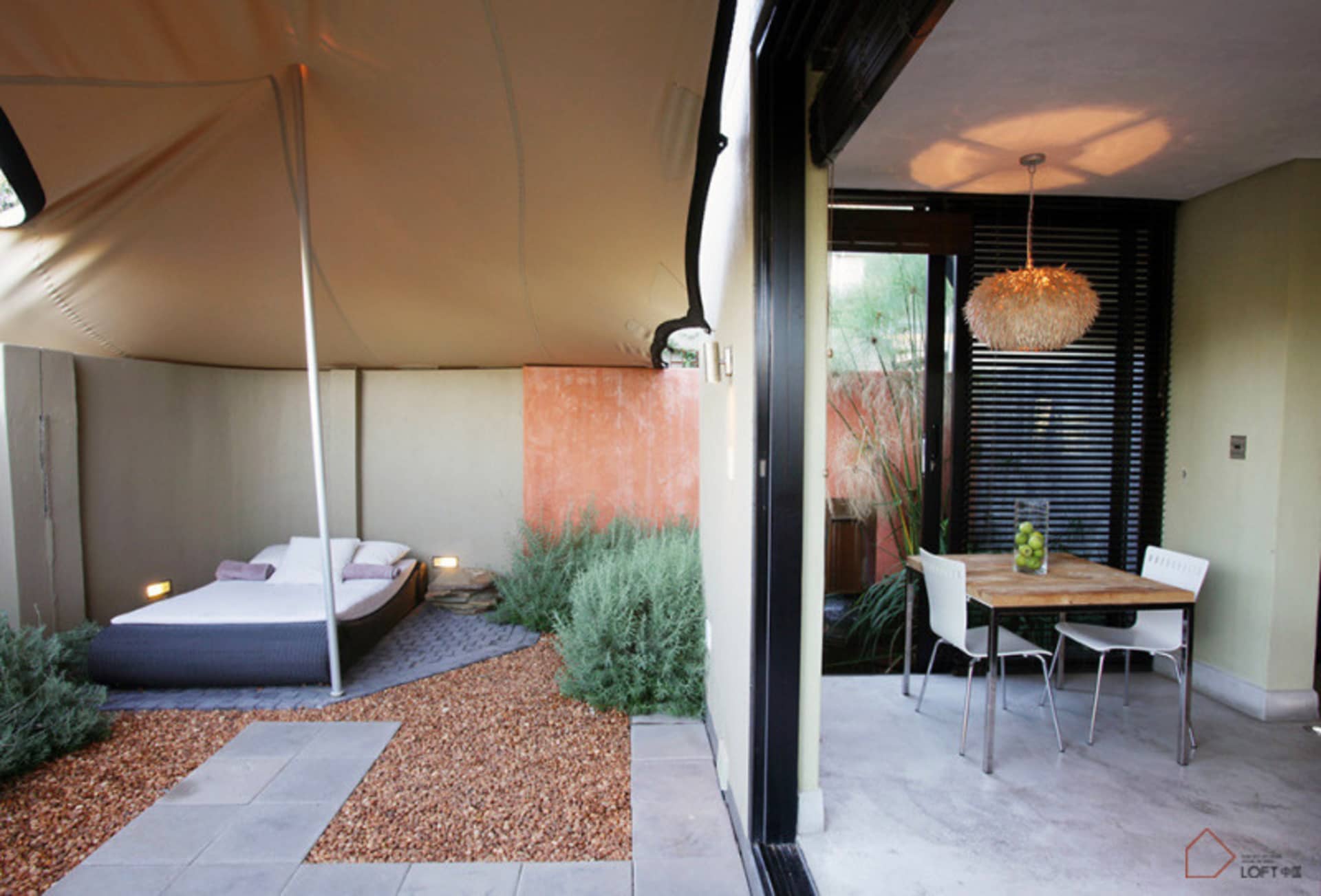 Minimalist residential patio featuring concrete flooring, wood dining table, and metal chairs.