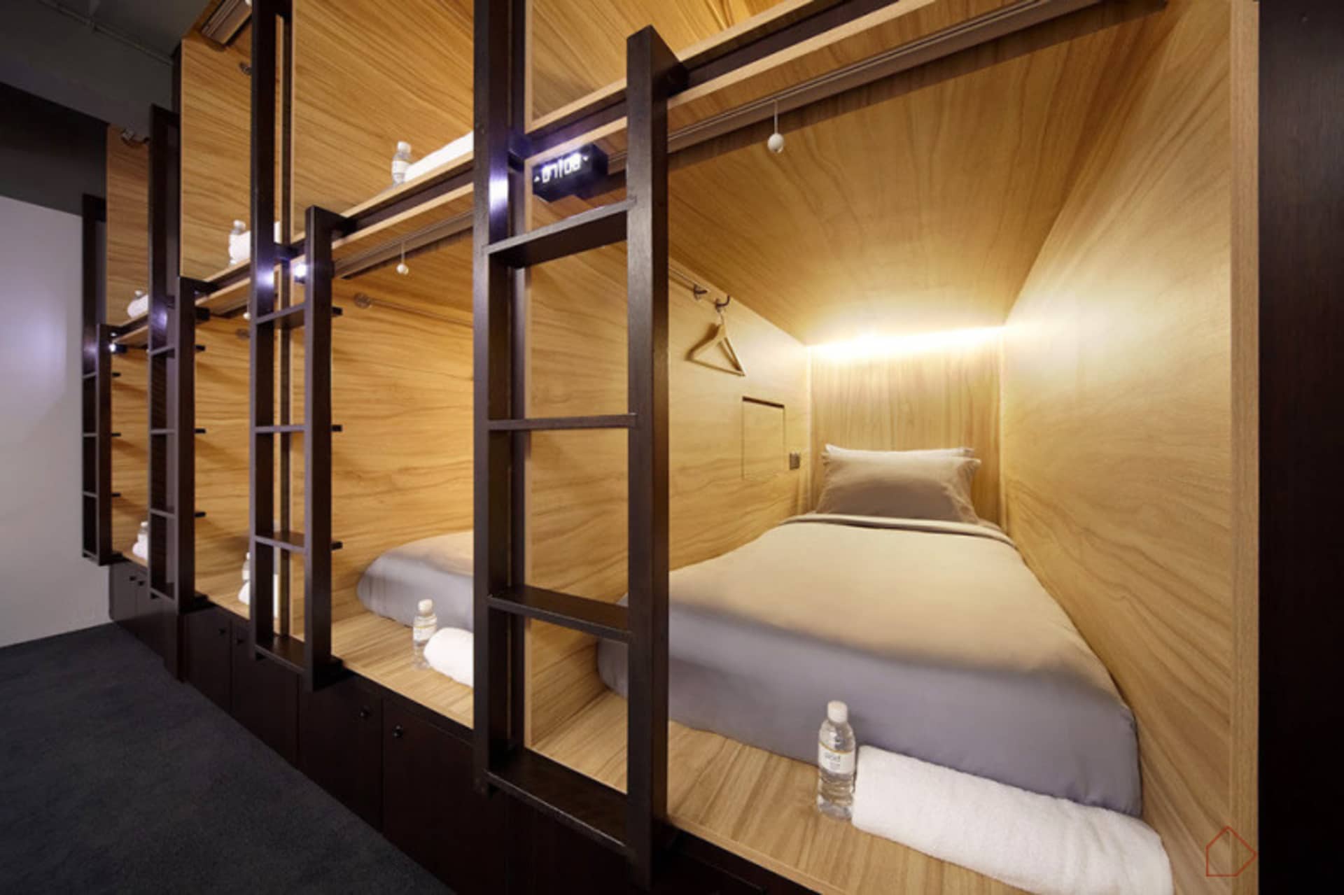 A minimalist bedroom with wooden walls and bed frame, featuring a ladder for easy access to the sleeping area.