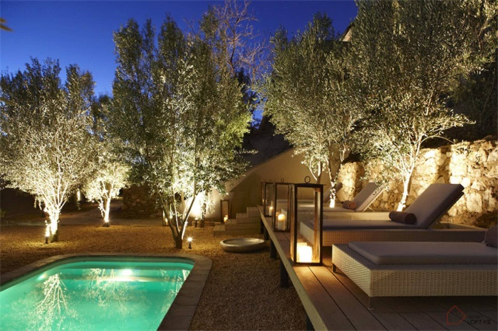 A modern residential patio with concrete flooring, outdoor furniture, and landscaped greenery.