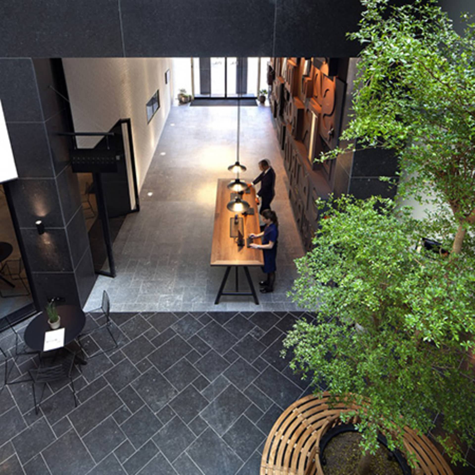 Industrial-style lobby with stone tiles, cement, and a central wooden table.