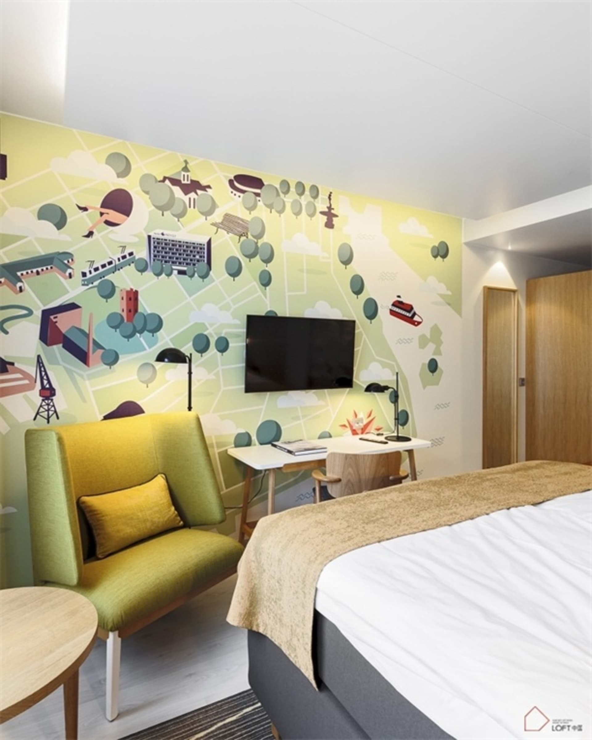 A minimalist bedroom with a green upholstered chair, a bed with a white mattress and beige cover, and a wall mural depicting