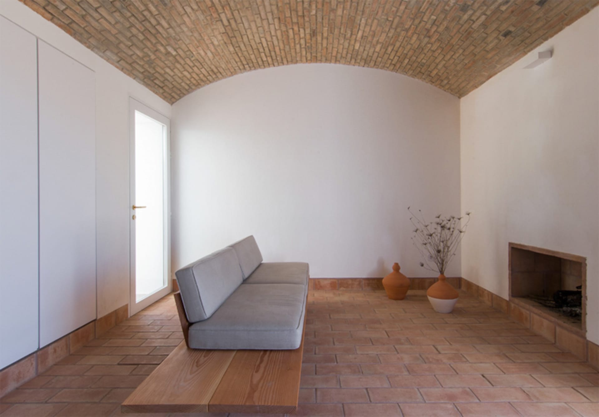 A minimalist living room with a terrazzo floor and a gray sofa.