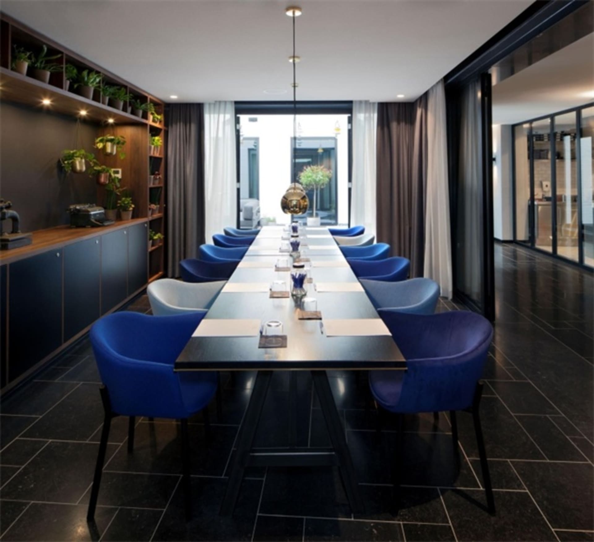 The conference room features sleek, metallic tables and plush, blue leather chairs, creating a sophisticated and professional