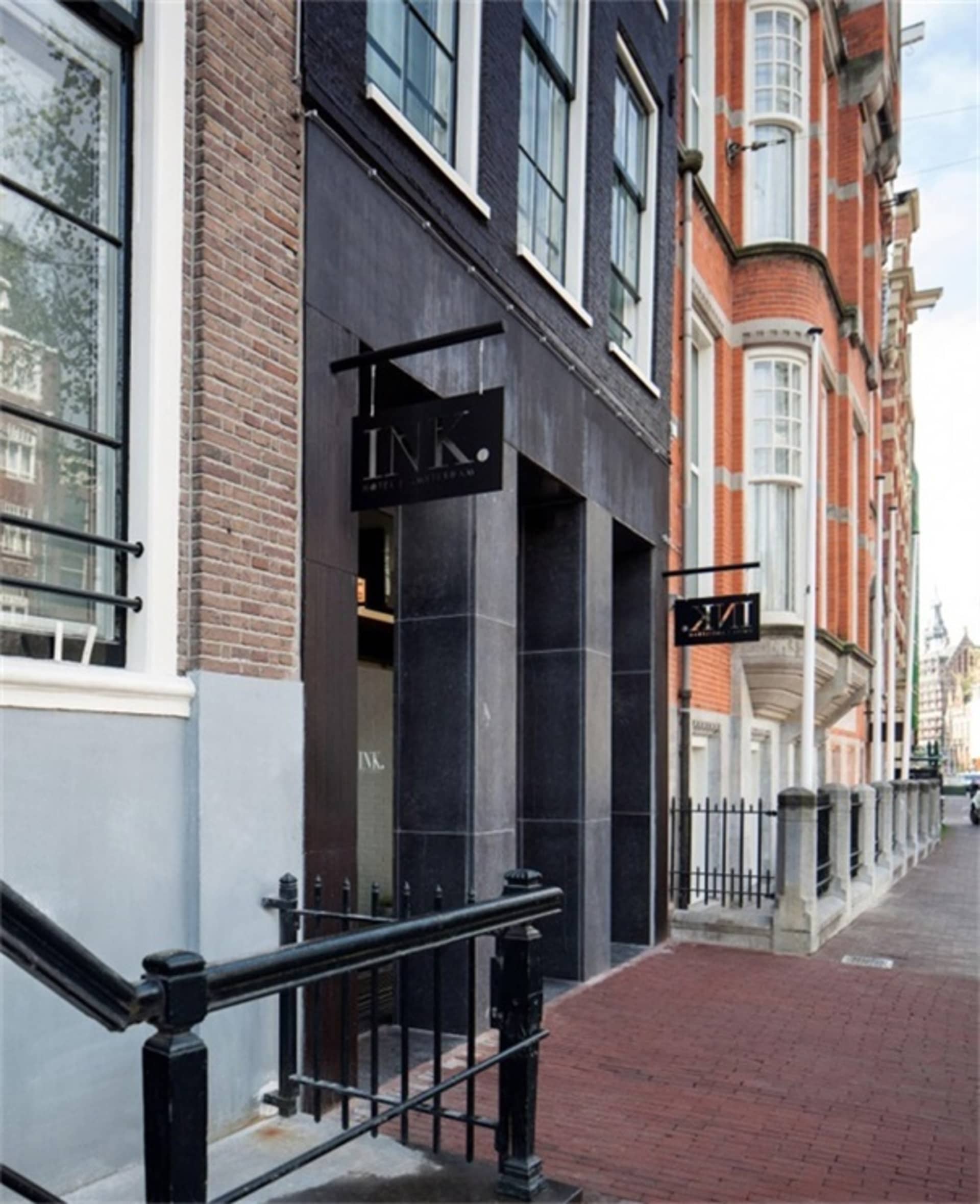 A view of a brick and concrete building with steel railings and a black sign with the text 'INK.'