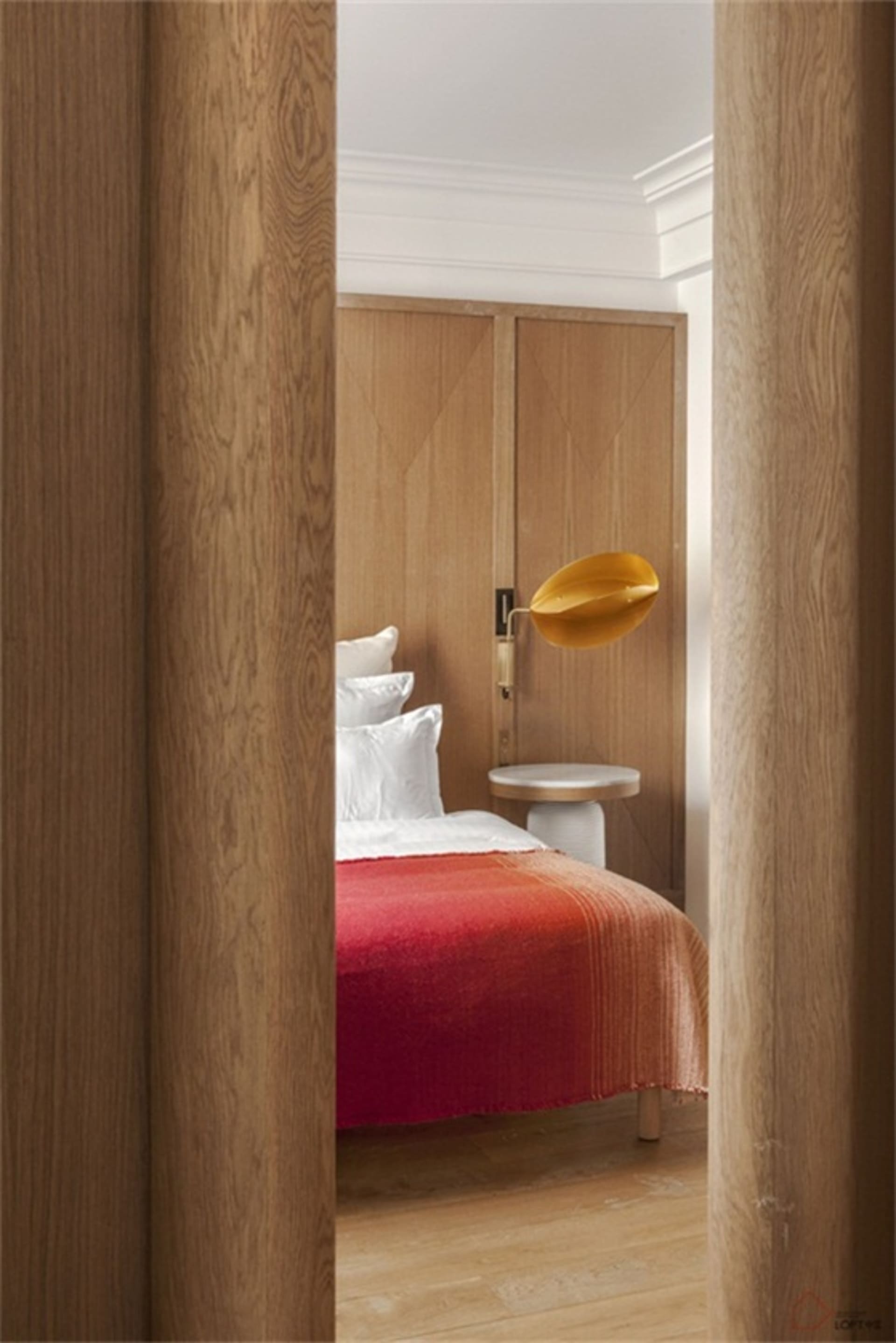 Minimalist bedroom featuring wooden furniture and a red blanket.