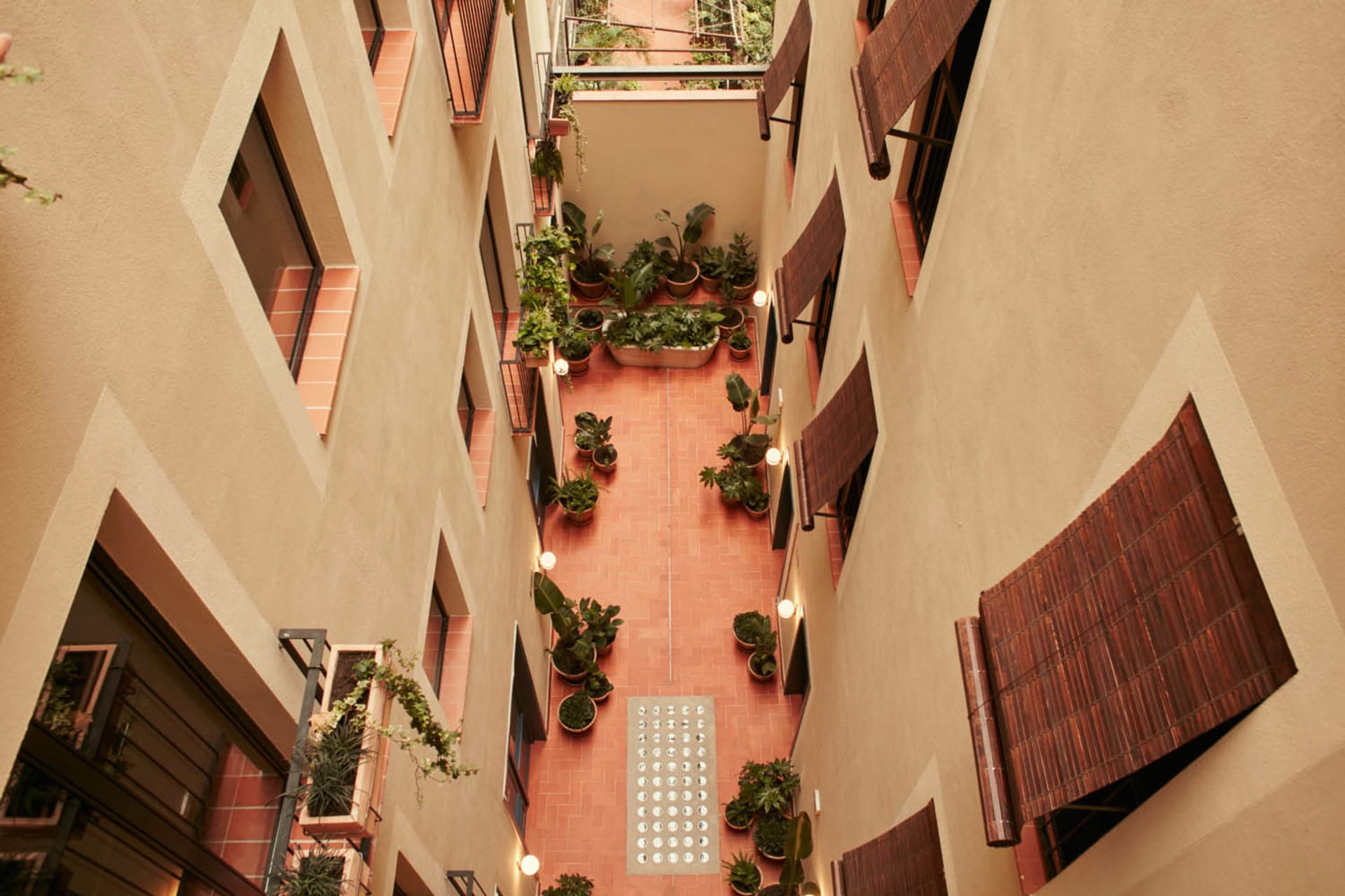 Modern, industrial-style courtyard facade with a terrazzo floor, greenery, and natural light.