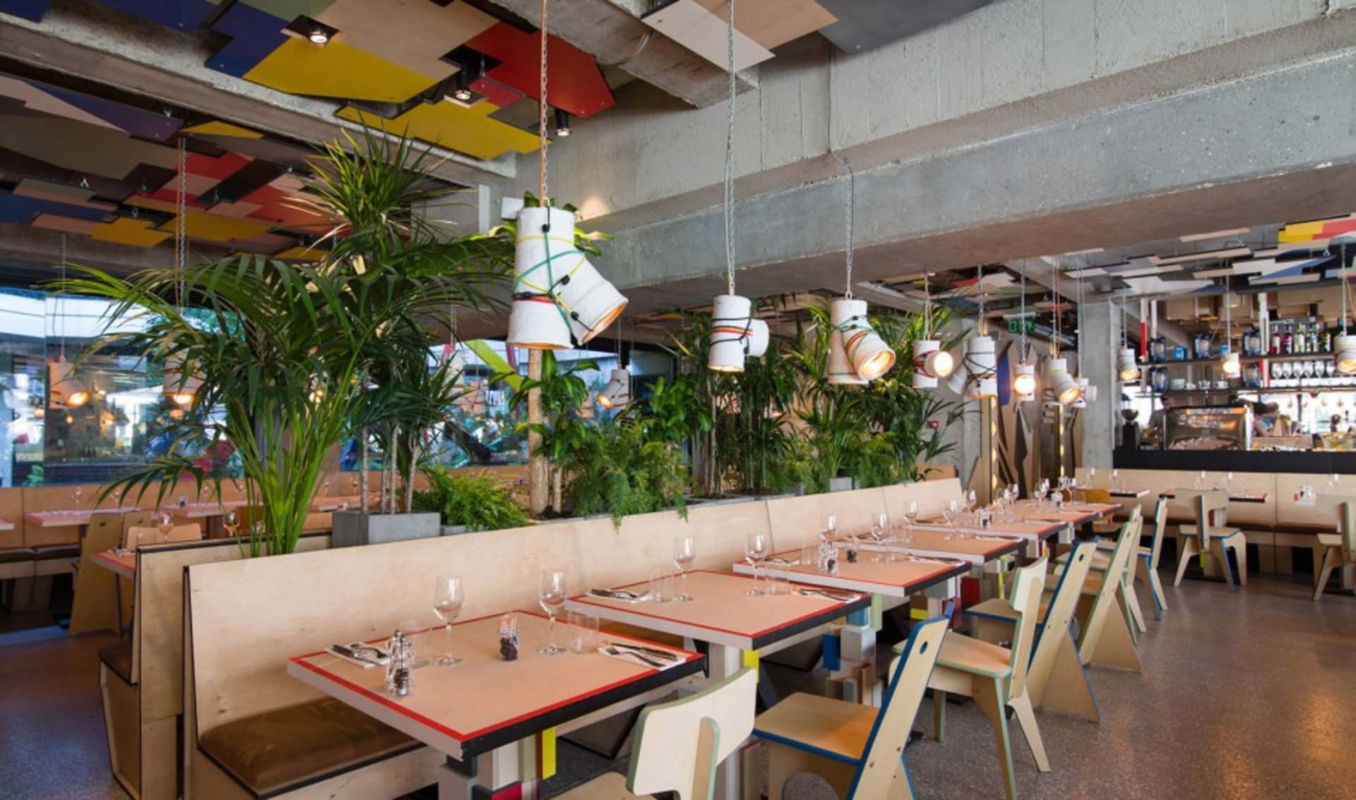 現代工業風餐廳室內，採用混凝土地板、木質家具與綠色植物。
