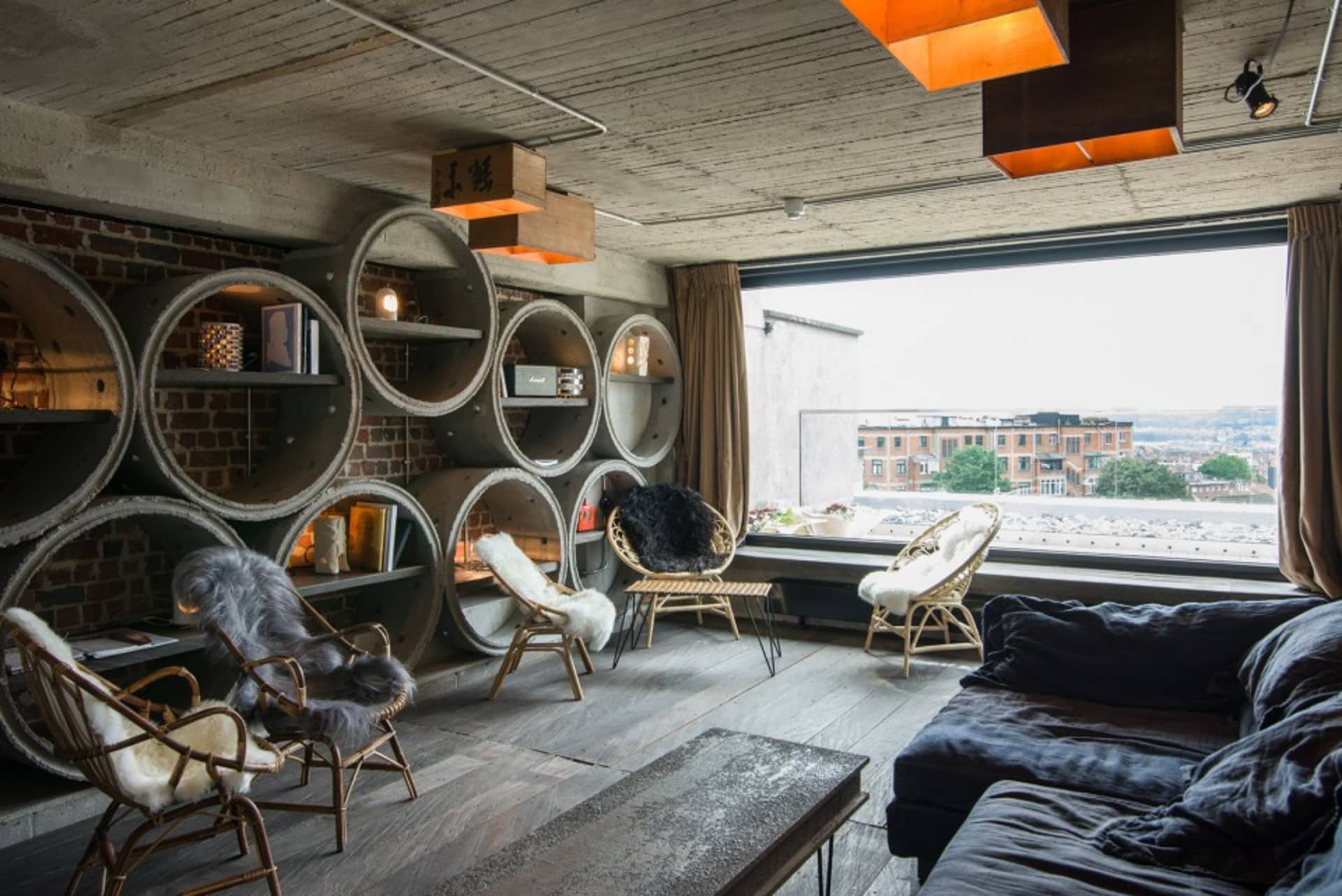 A spacious living area featuring industrial-style concrete pipes and a rustic wooden interior.