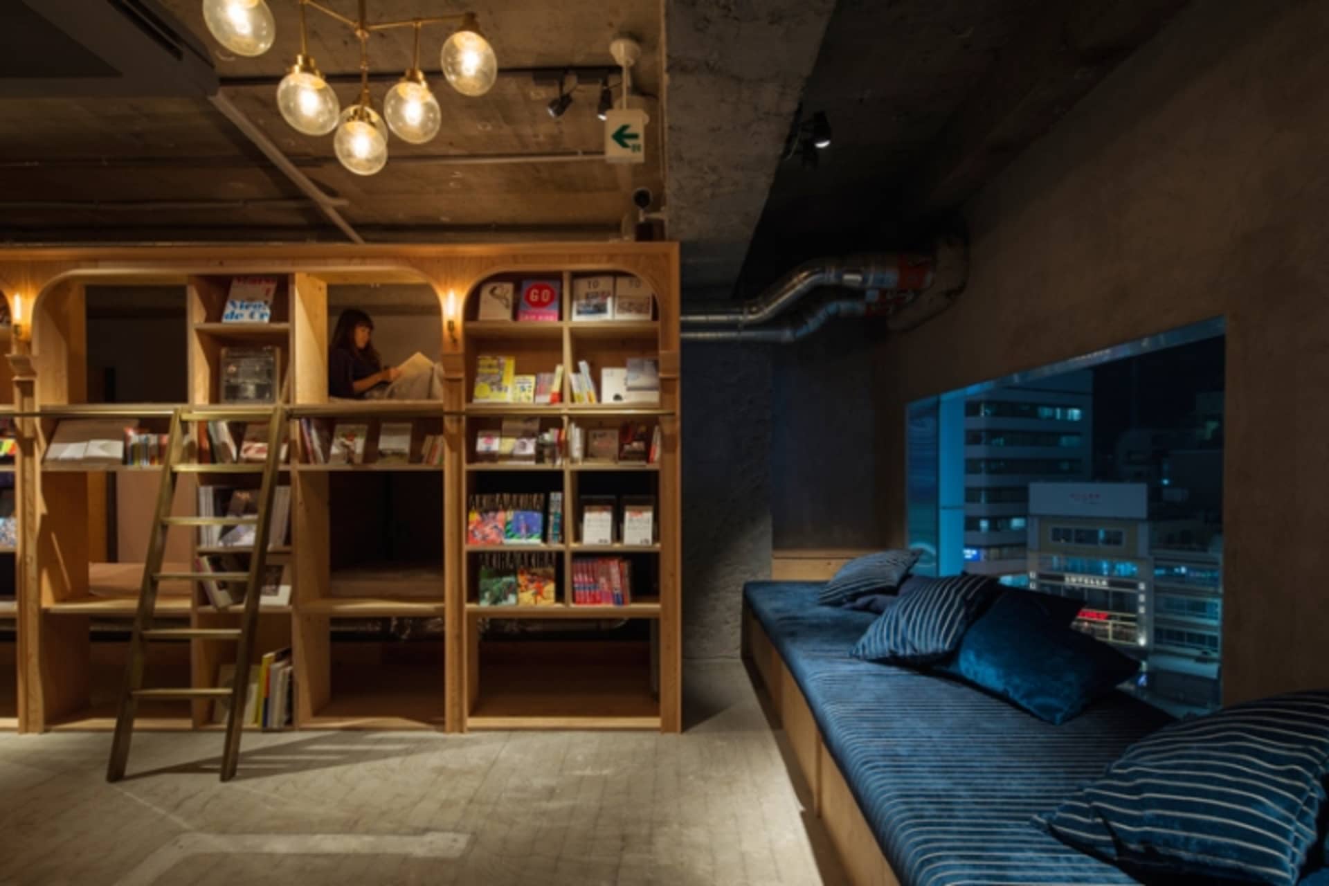 簡約圖書館室內,採用混凝土與木質表面,並設有通往高處書架的梯子。