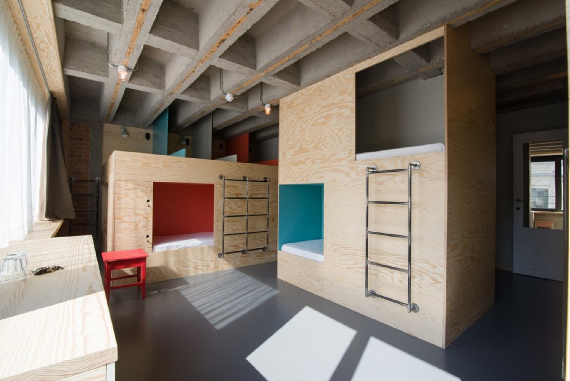 Modern minimalist bedroom with wooden bunk beds and red accents