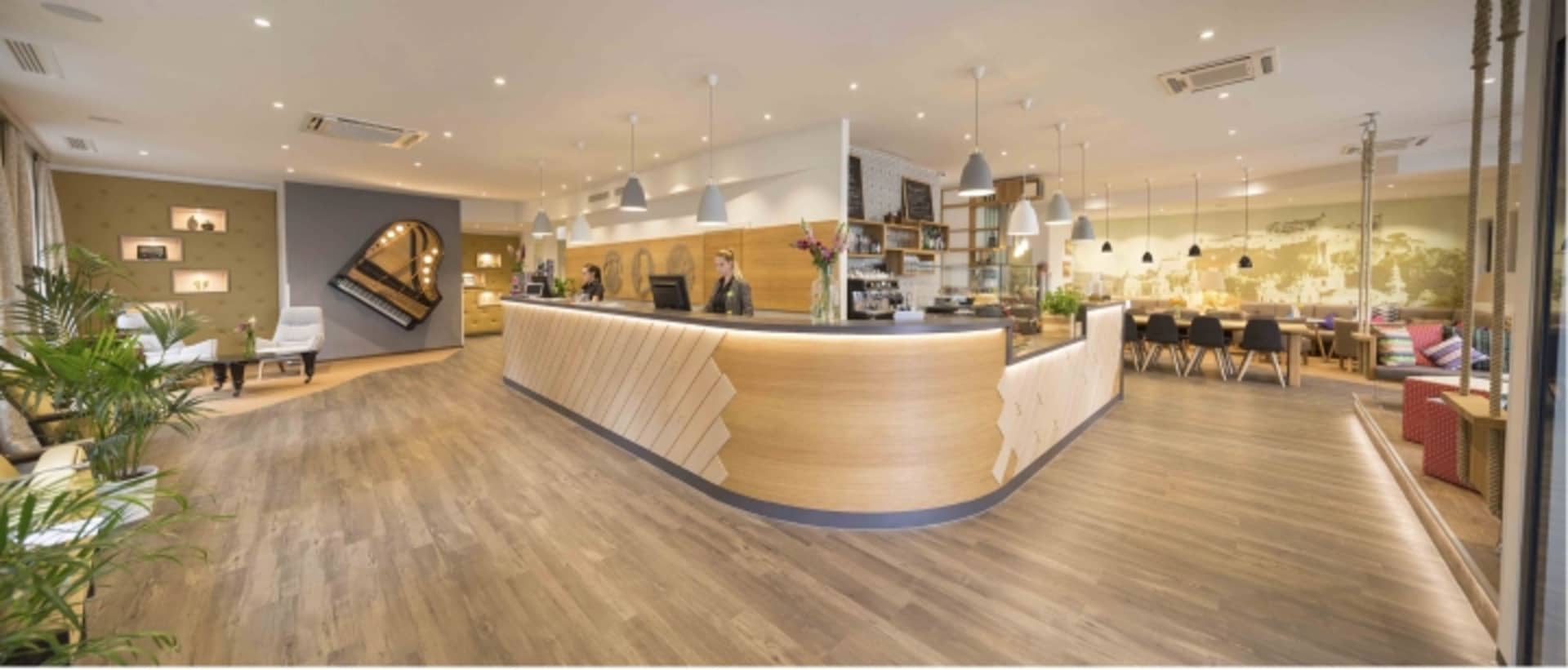 An inviting modern cafe reception area with wooden countertops, a world map backdrop, and a piano.