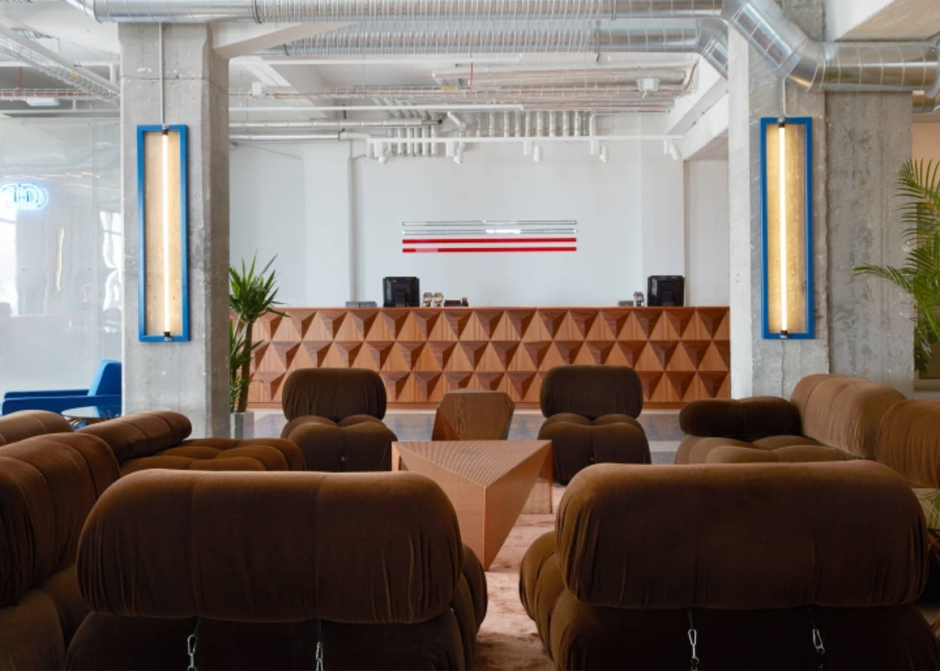 A spacious industrial-style officeITOR with a modern wooden reception desk and comfortable seating arrangements.
