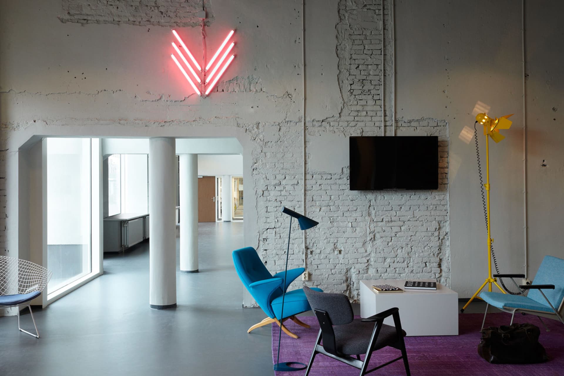 Minimalist office space featuring a concrete wall and blue chairs.