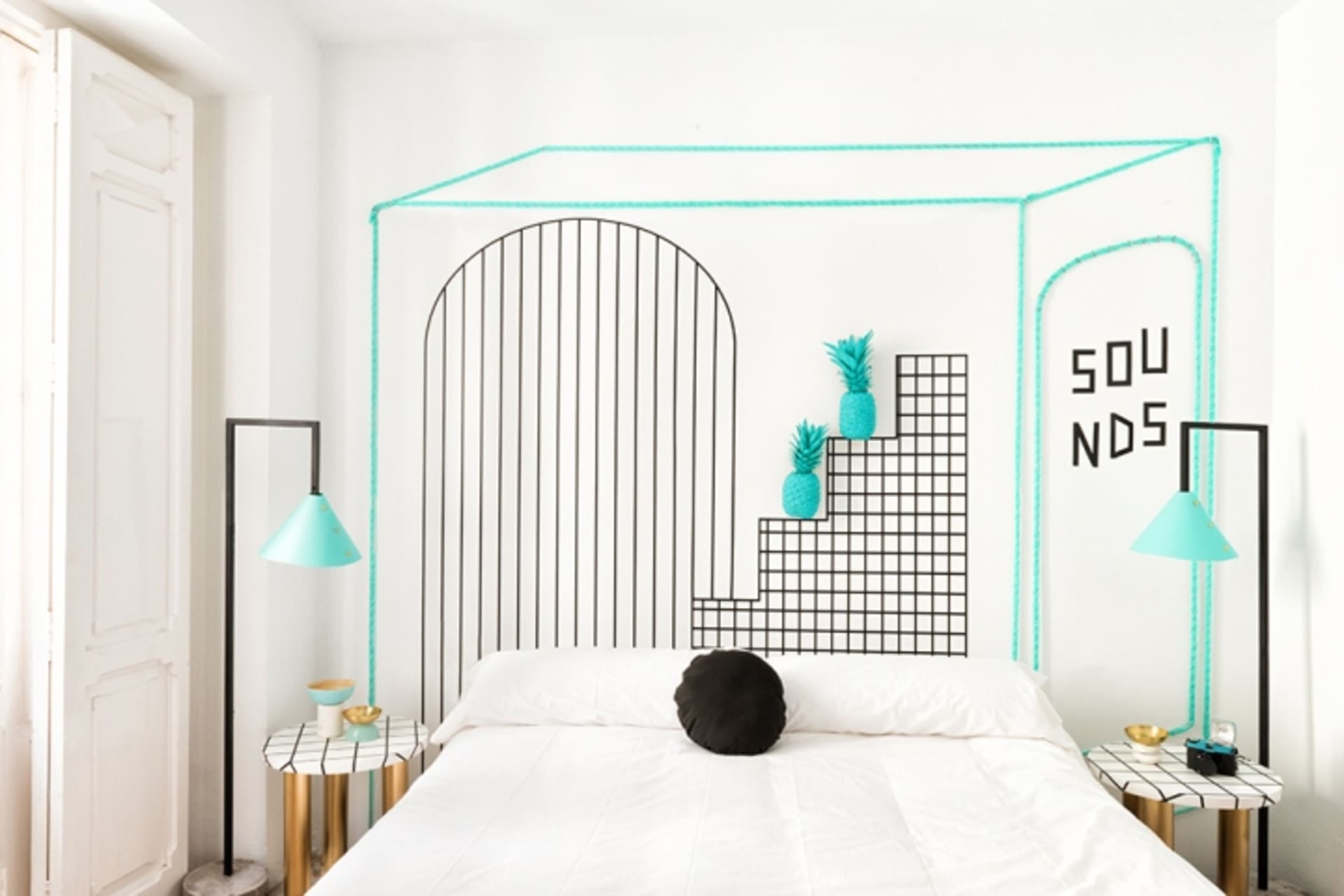 A modern bedroom featuring a turquoise accent wall with a geometric wire design and metallic elements.