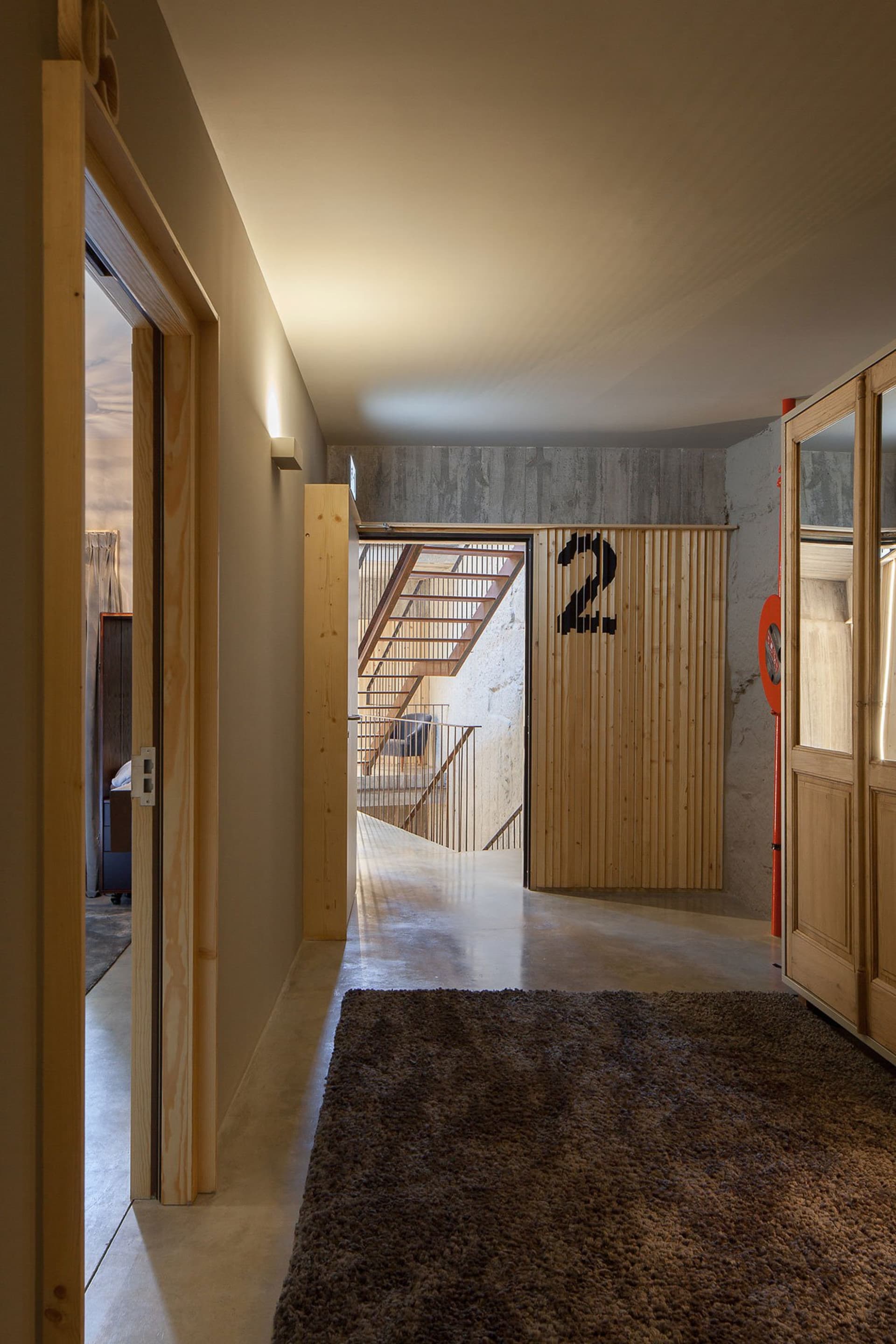 A modern residential interior featuring concrete flooring, wood walls, and metal railings.