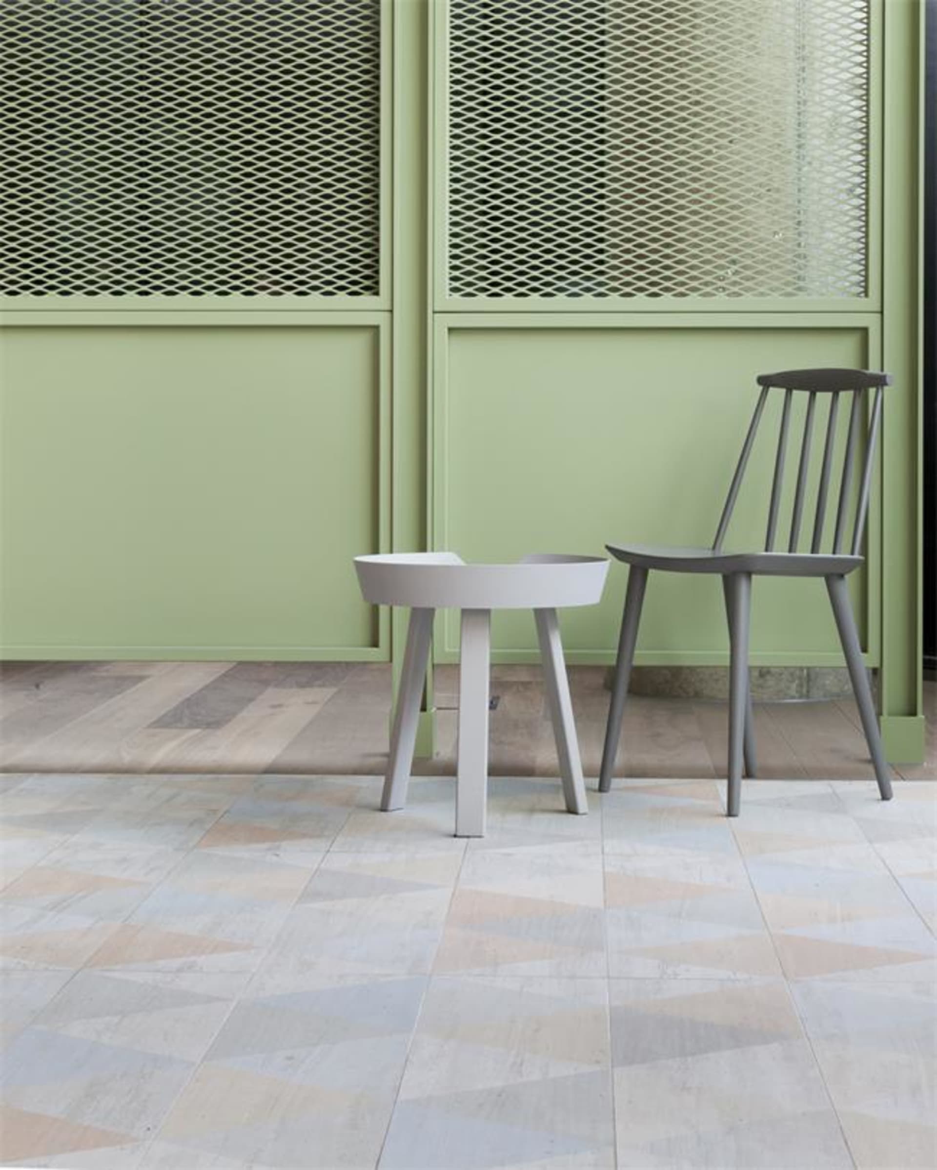 A modern interior design featuring a tiled floor, concrete furniture, and green paneling.