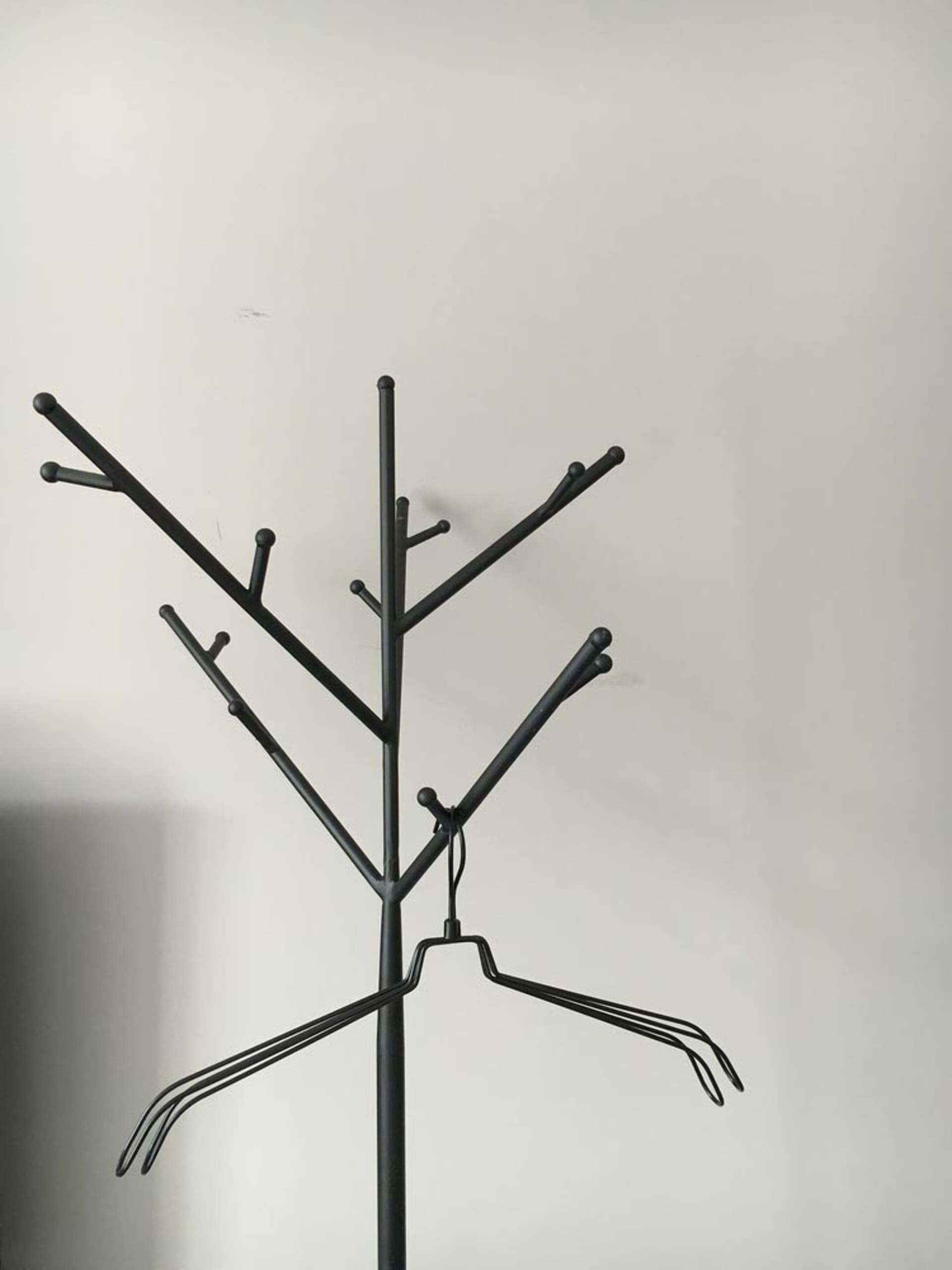 A modern metal tree rack with multiple hooks and hangers.