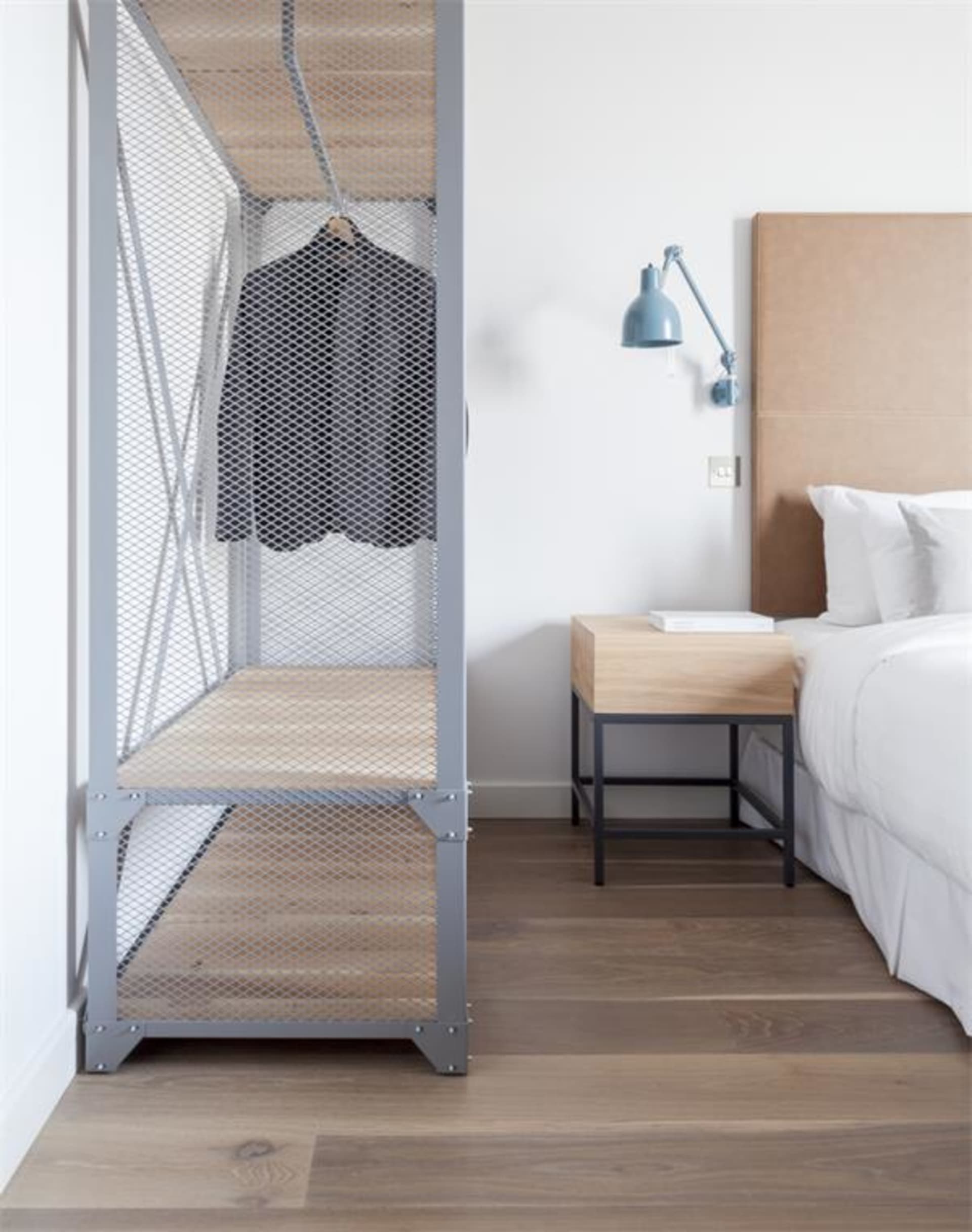Industrial-style bedroom with floating wooden shelves, modern bed, and minimalist decor.