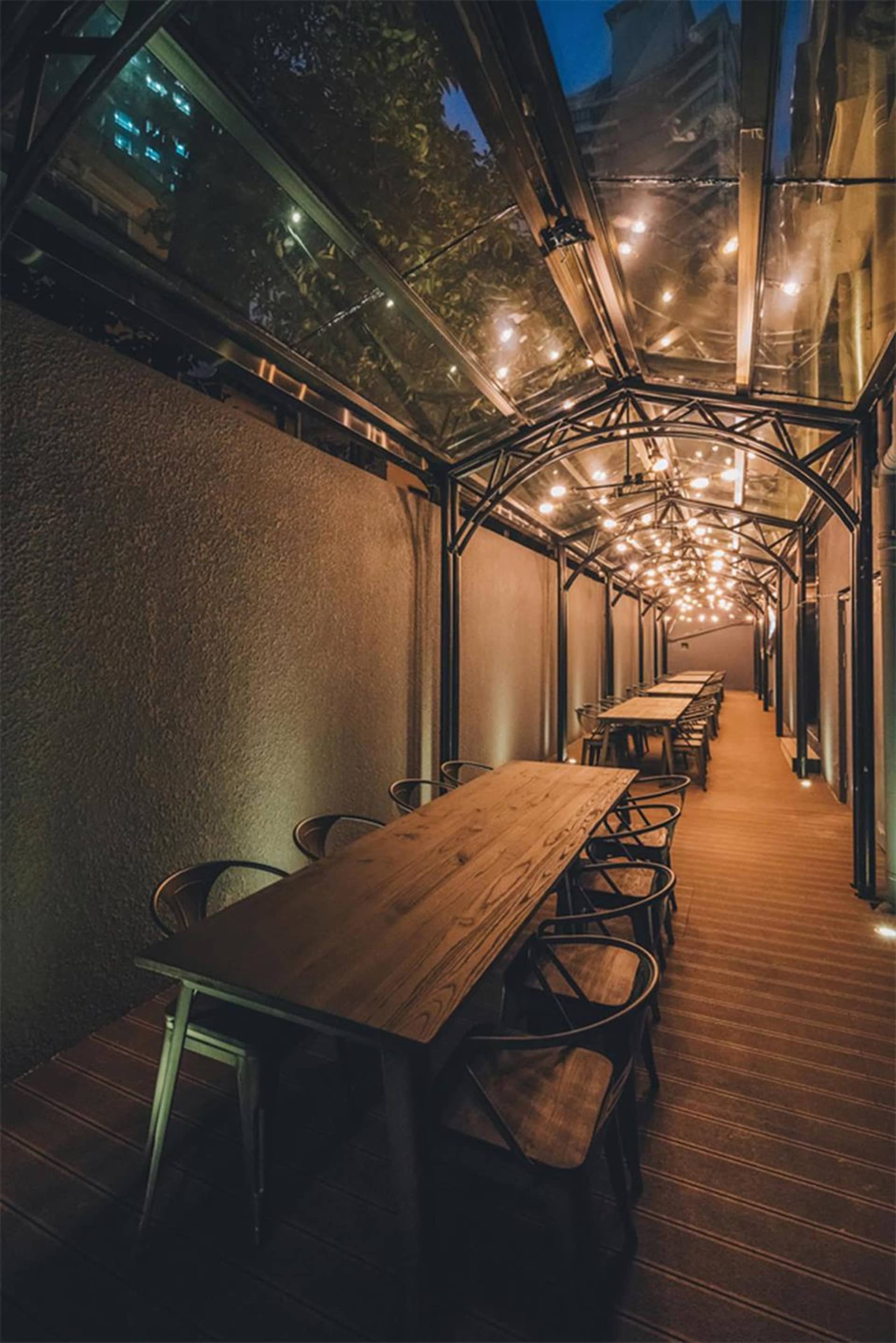 現代工業風餐廳外觀，搭配木製餐桌、金屬椅與玻璃天花板。