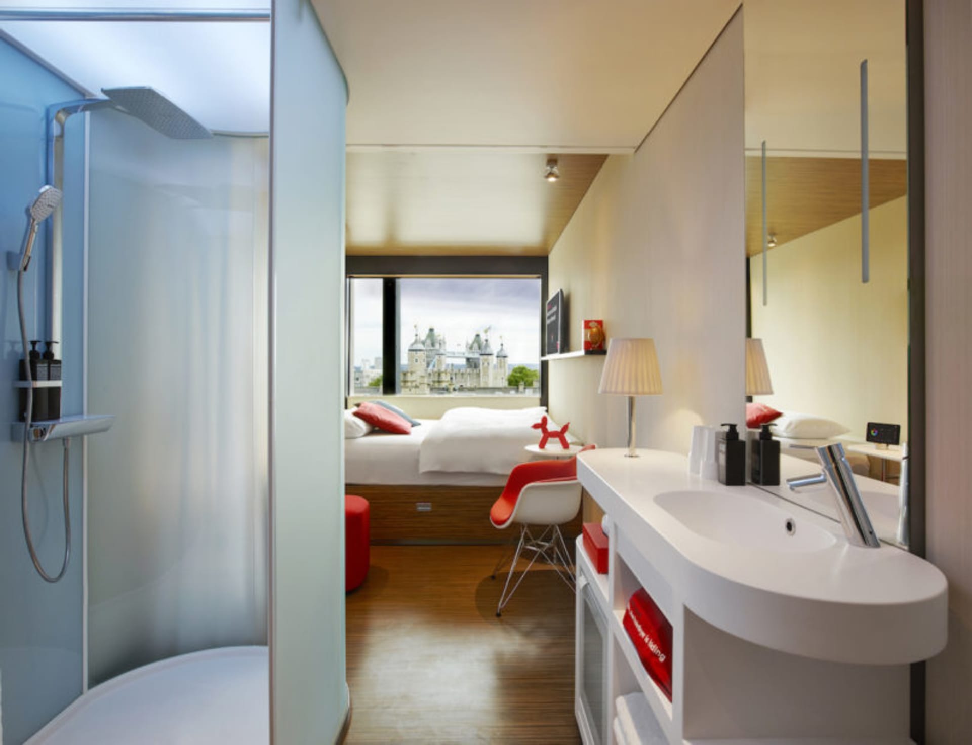 Contemporary hotel room featuring a white wash wall, wooden floors, and a view of an architectural landmark.